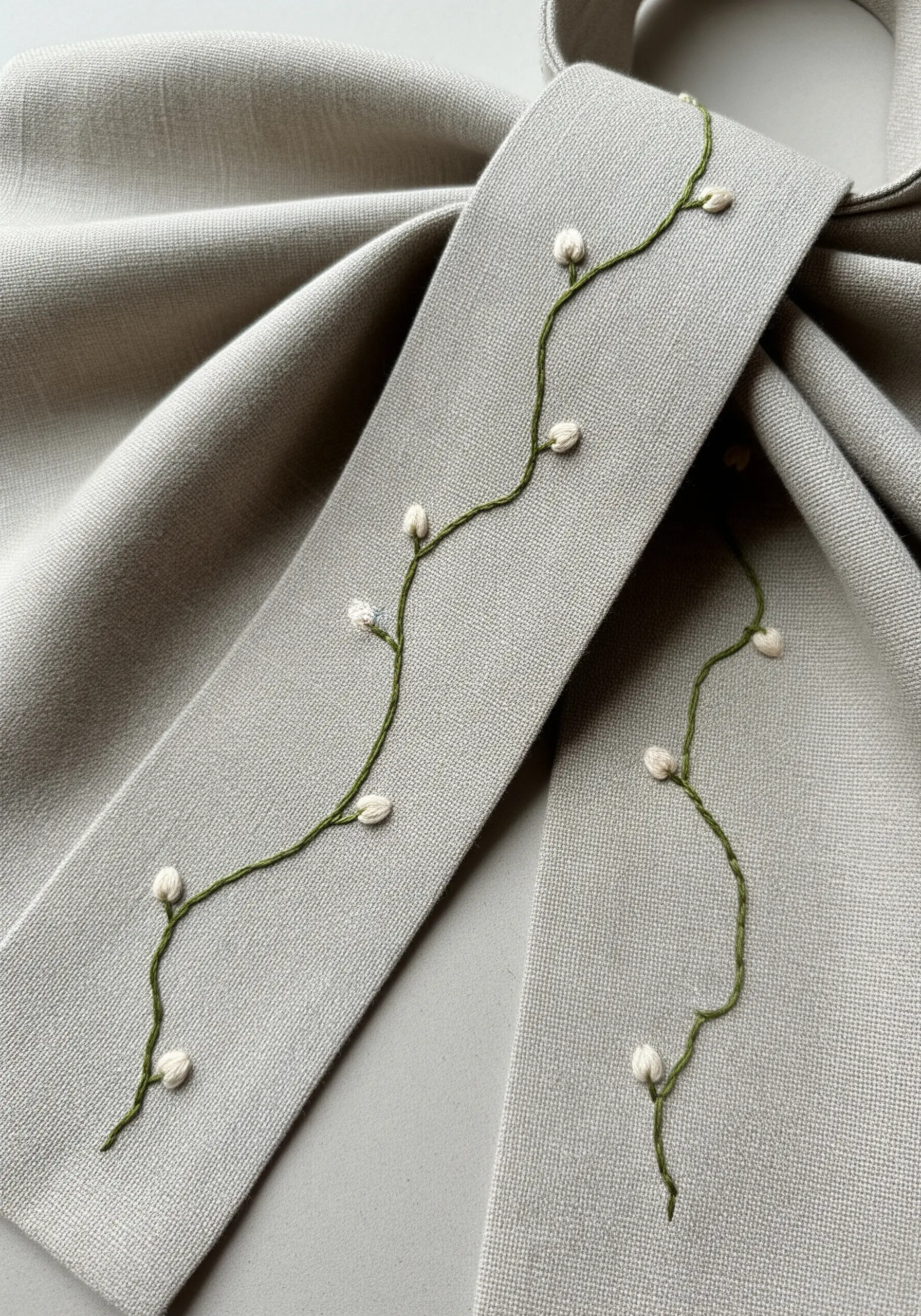 A delicate green vine with small white bullion knot flower buds.