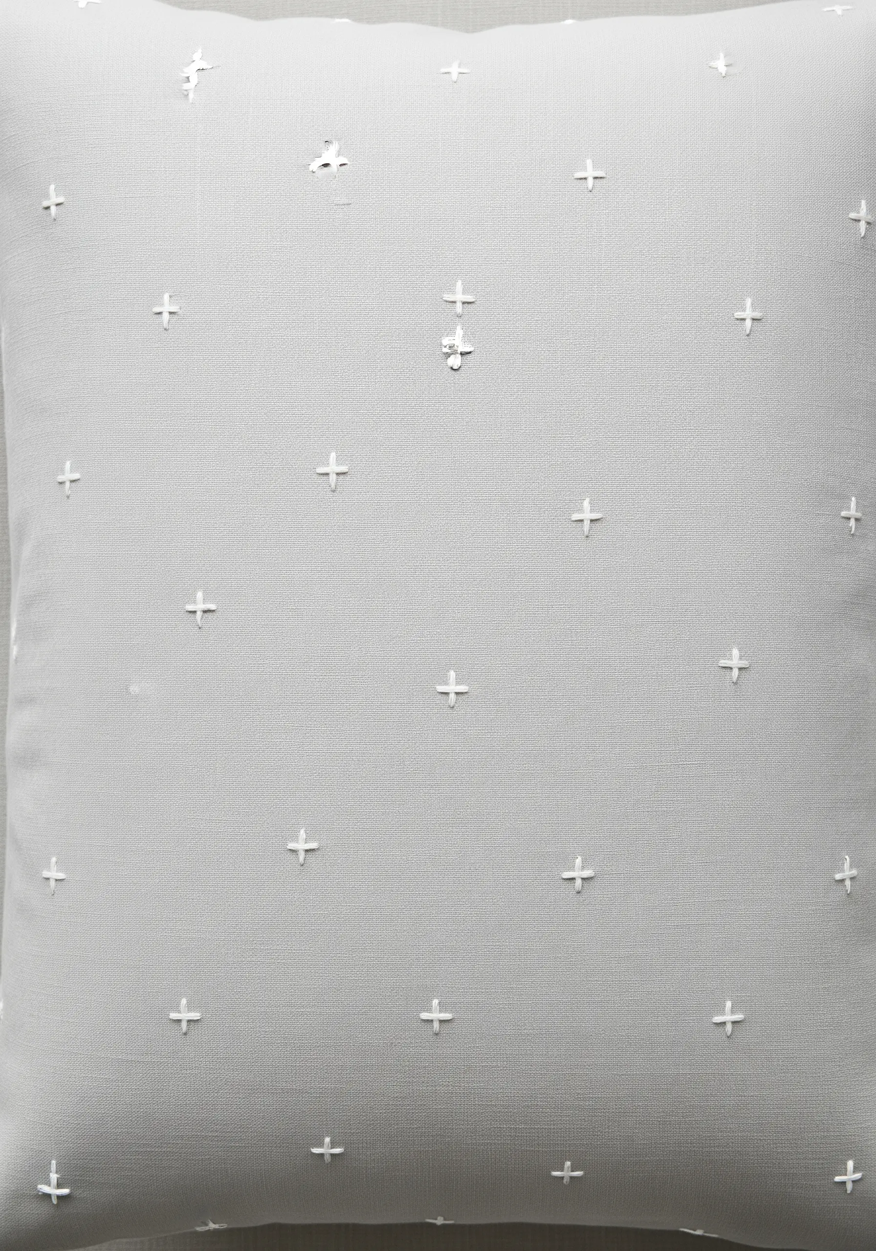 A scatter pattern of white embroidered plus signs on a grey pillow.