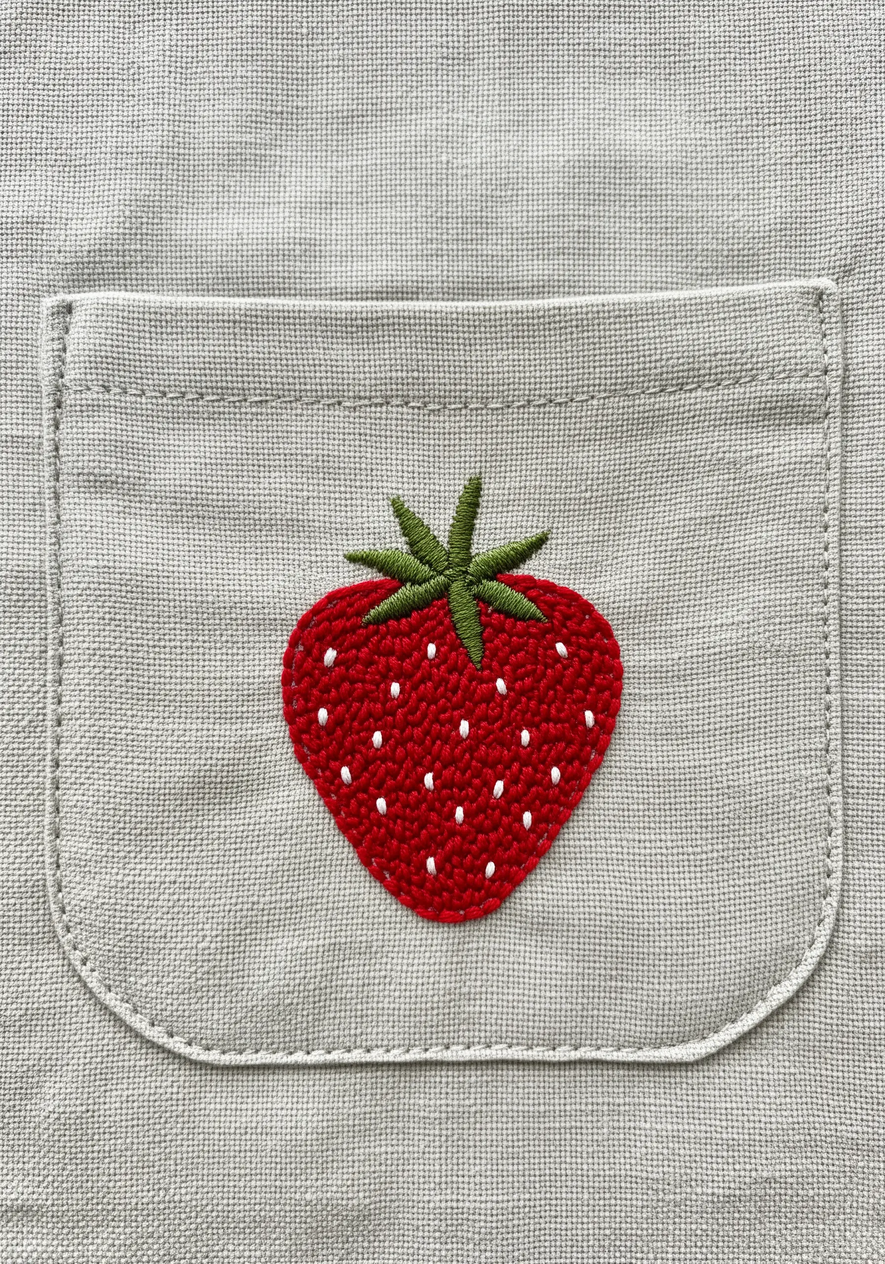 A textured, woven-fill strawberry with French knot seeds on a pocket.