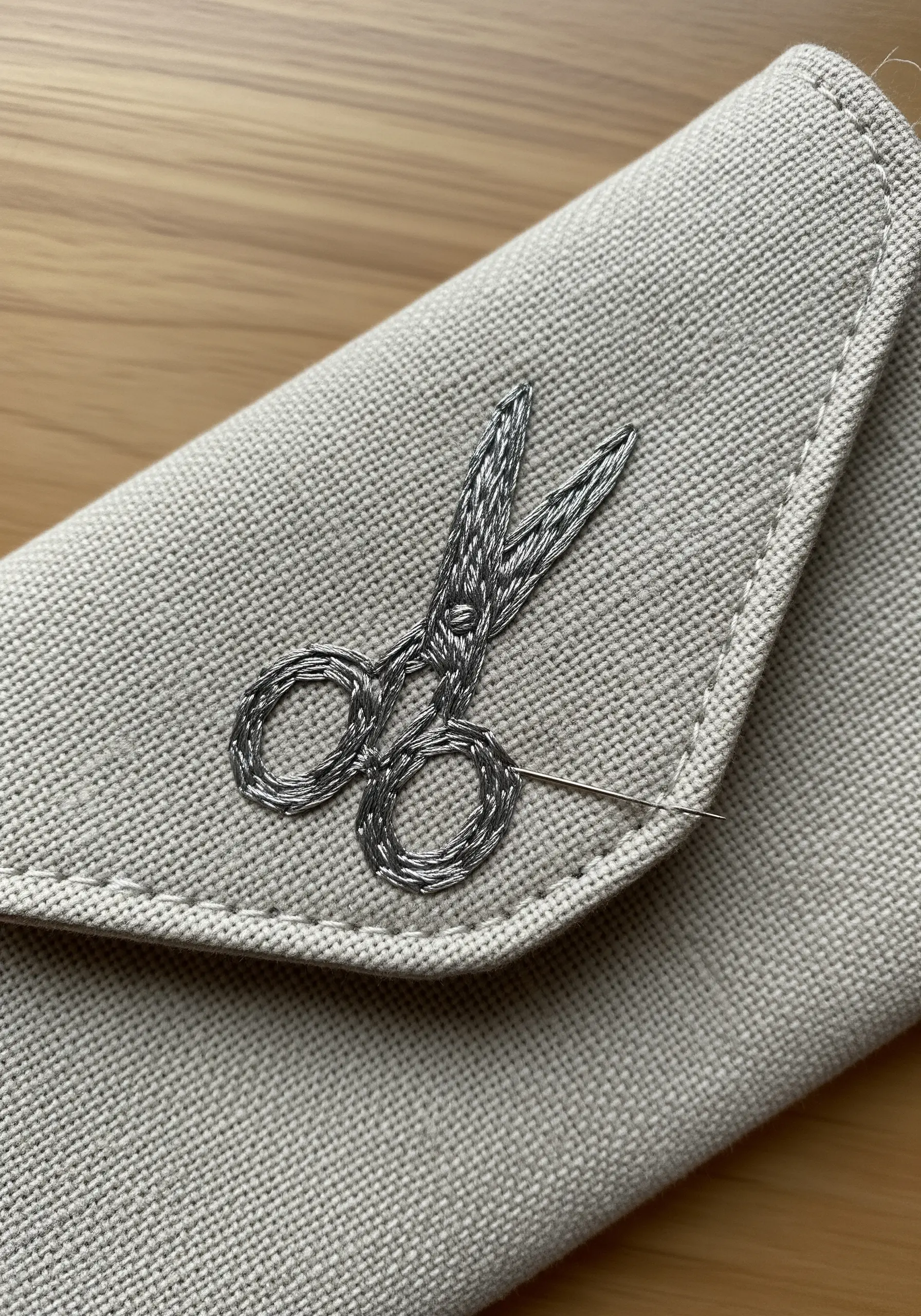 A pair of scissors embroidered with a woven stitch technique to create a metallic texture.