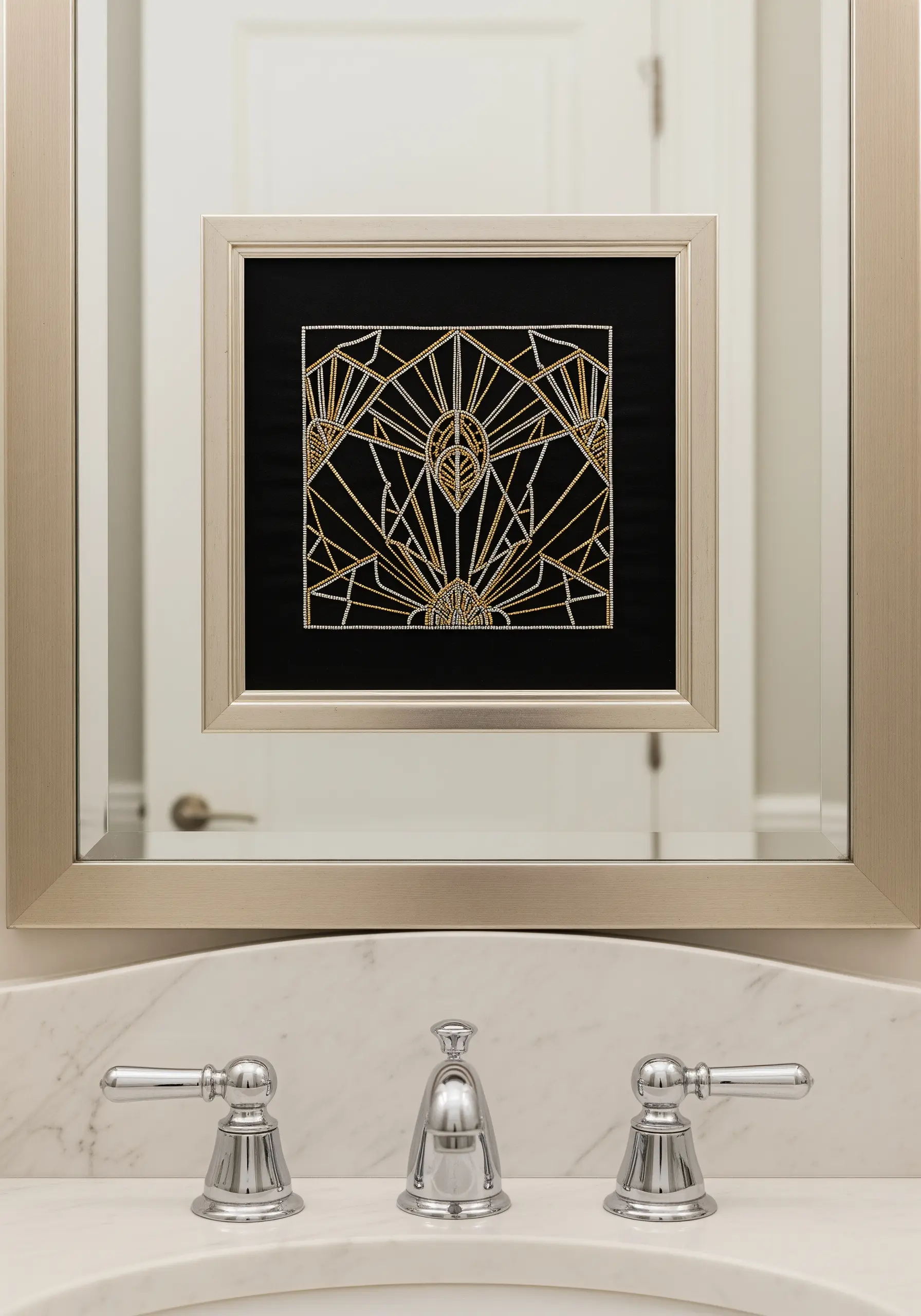 A framed Art Deco embroidery design in gold and silver metallic thread on black fabric.
