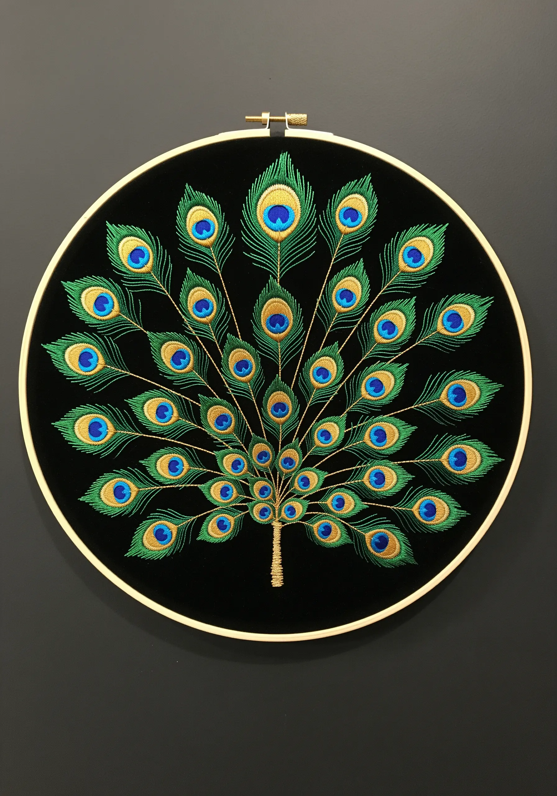 Embroidery of a fanned peacock tail on black velvet with metallic gold details.