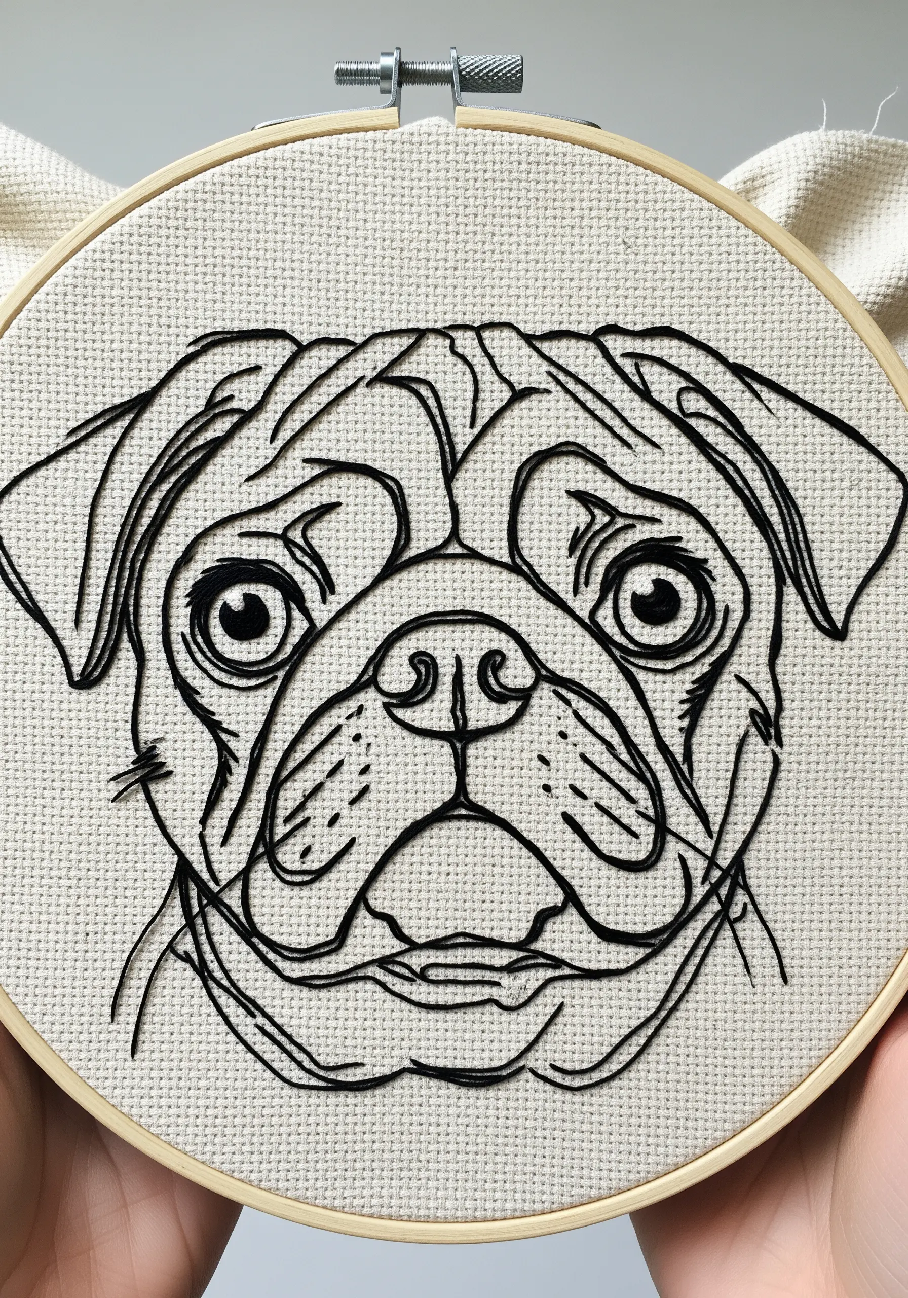 Close-up of a highly detailed line art pug face on evenweave fabric.