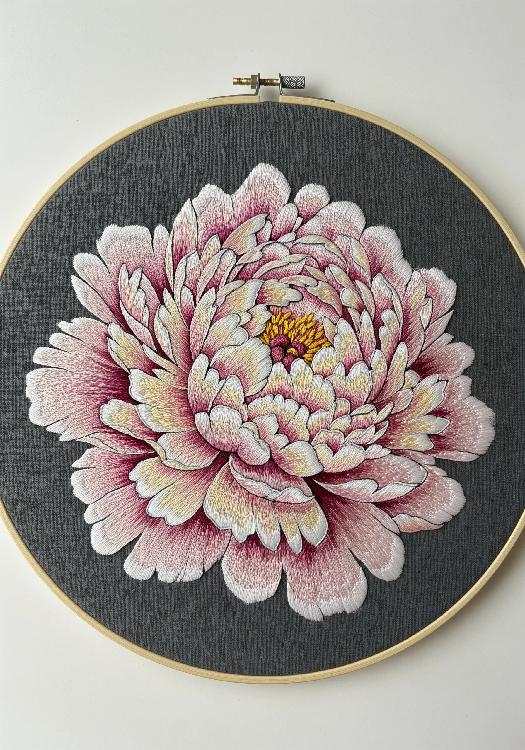 Thread-painted pink and cream peony on dark gray fabric in an embroidery hoop.