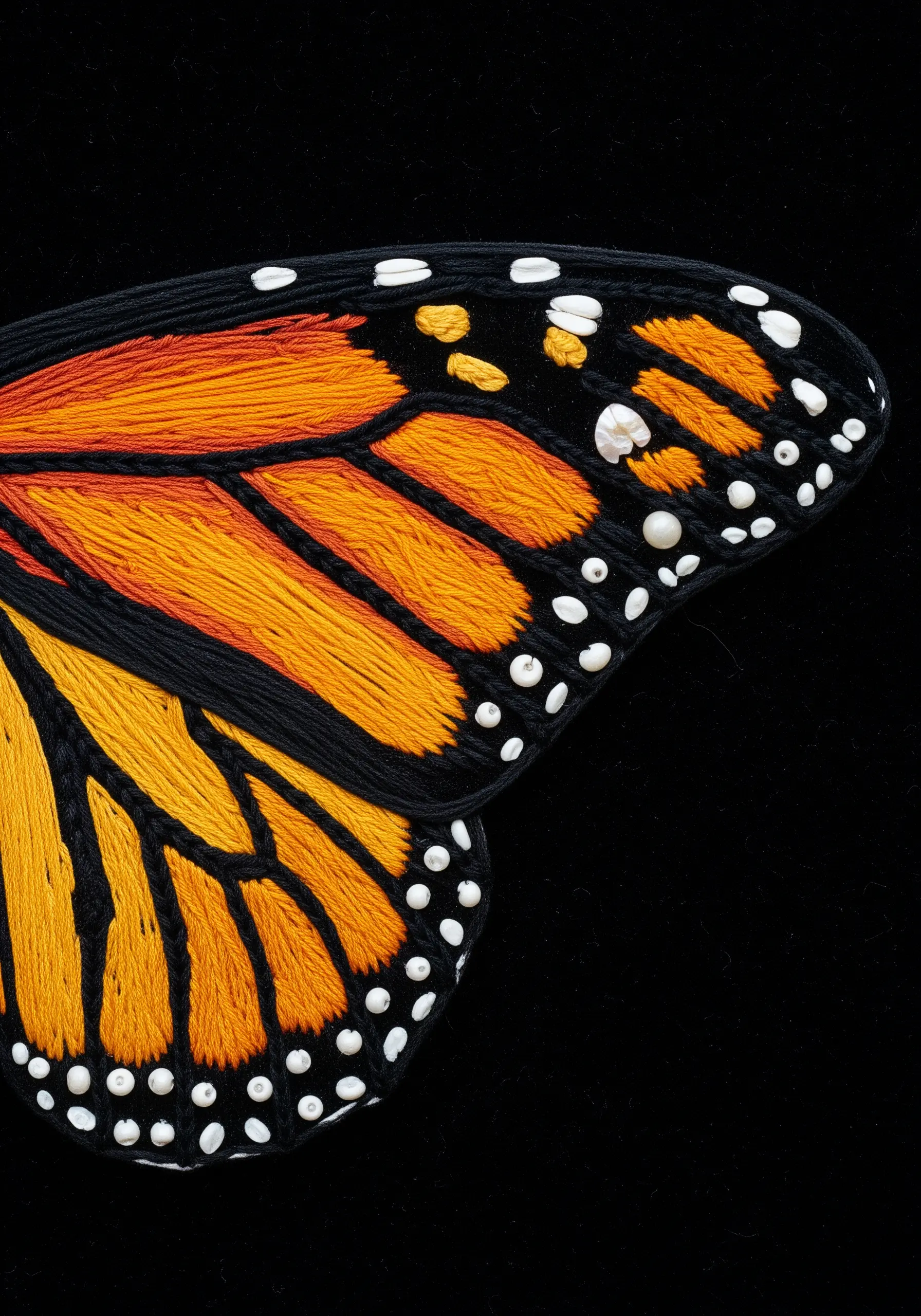Detailed embroidery of a monarch butterfly wing with smooth satin stitch and white bead details.