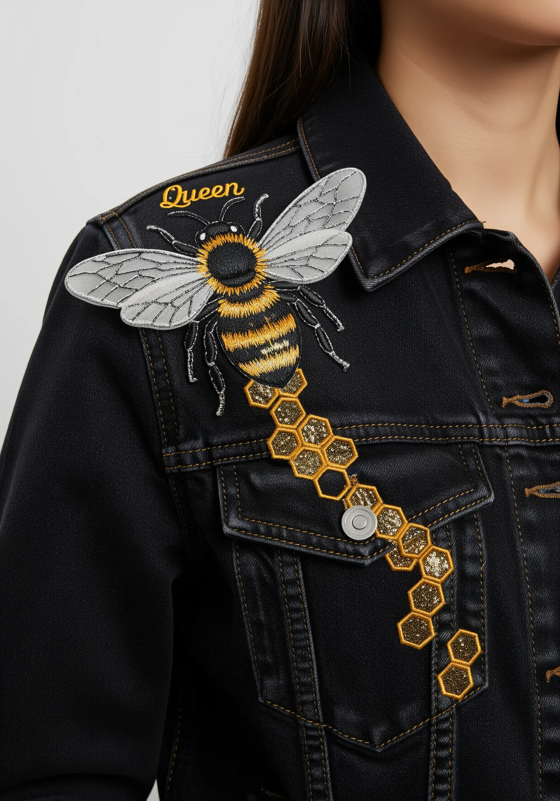 A large embroidered bee on a black jacket, with 3D wings and a trail of glittering honeycomb.