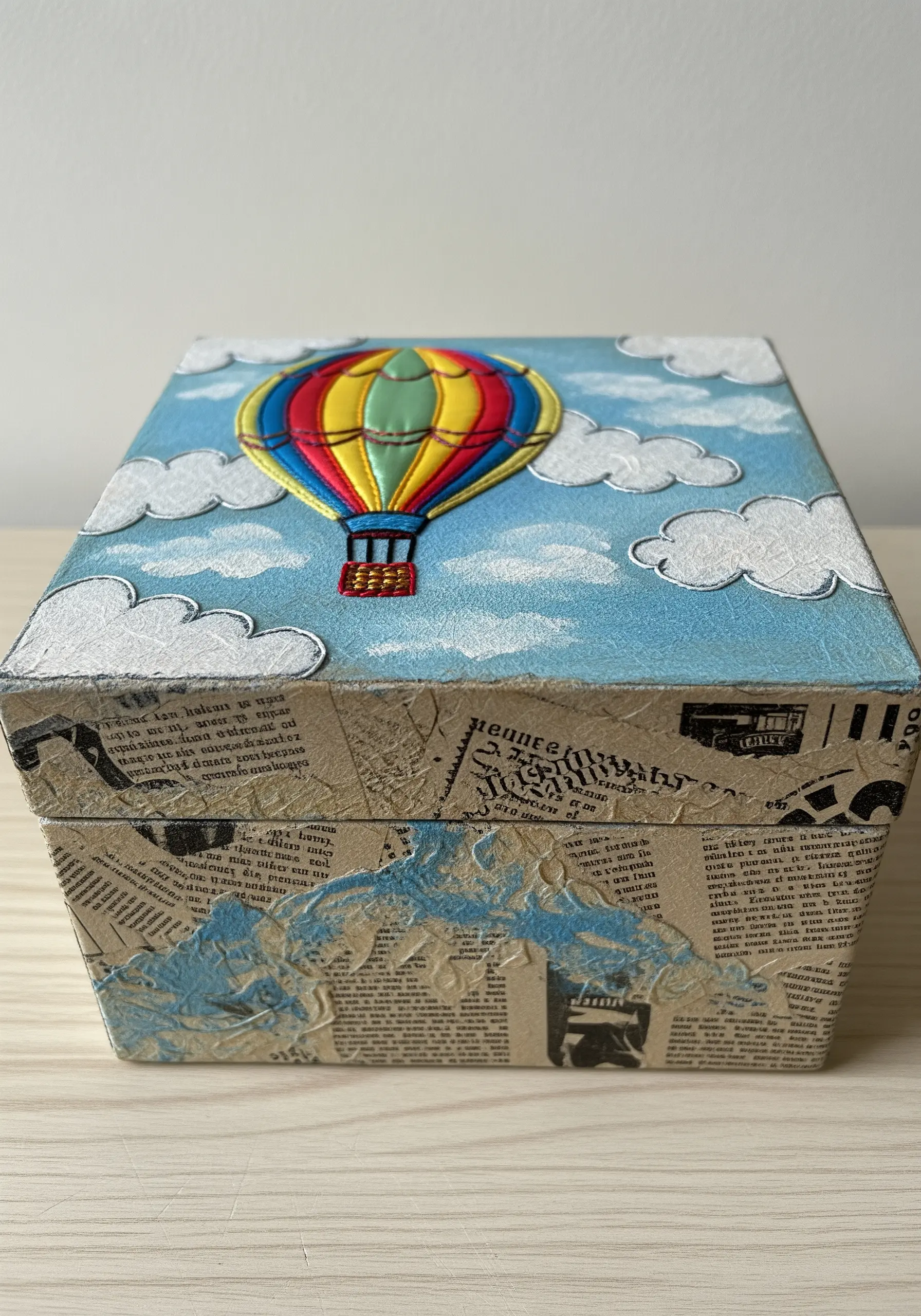 A decoupage box with a padded satin stitch hot air balloon appliqué on the lid.