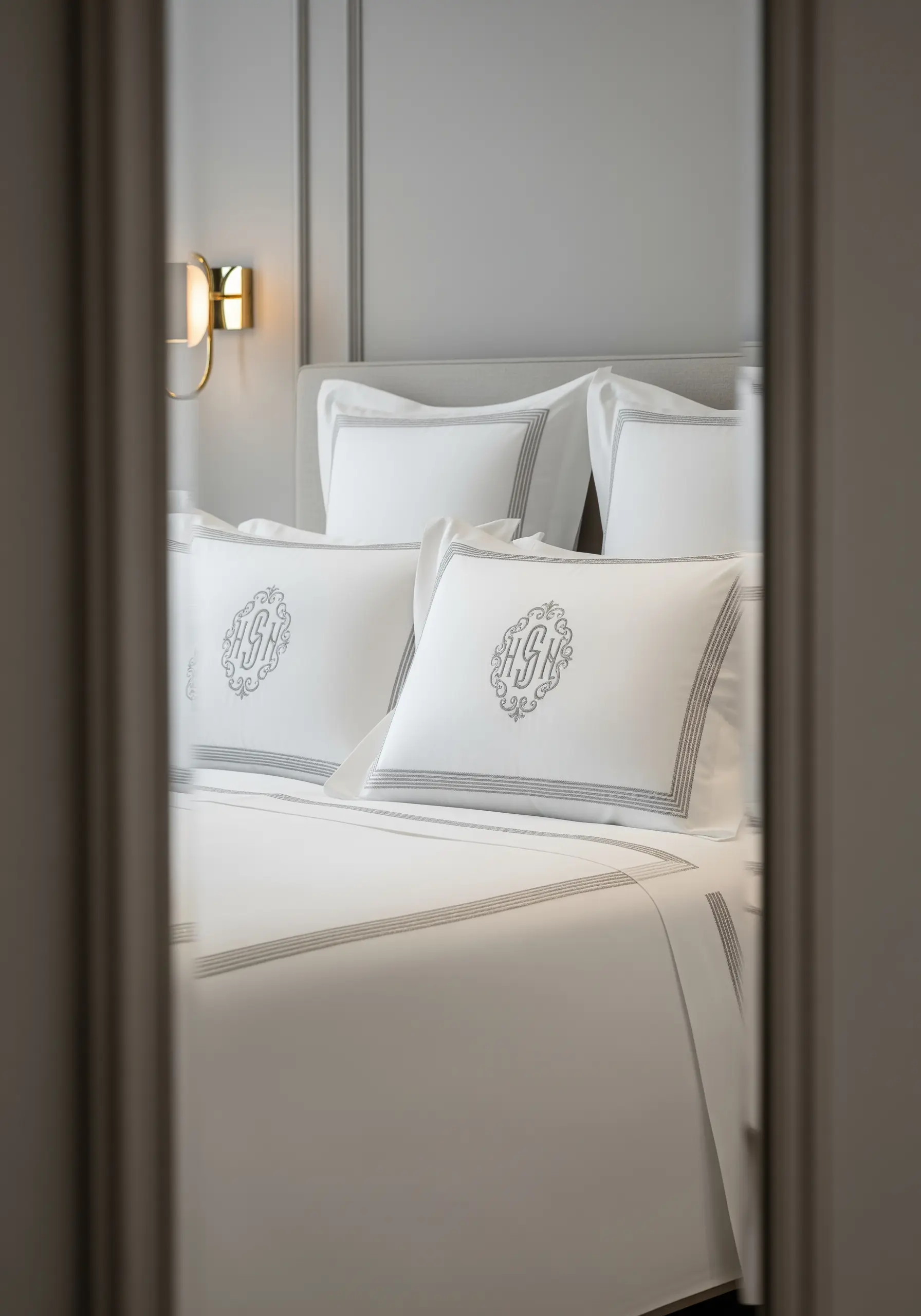 An elegant padded satin stitch monogram on a crisp white pillow sham.
