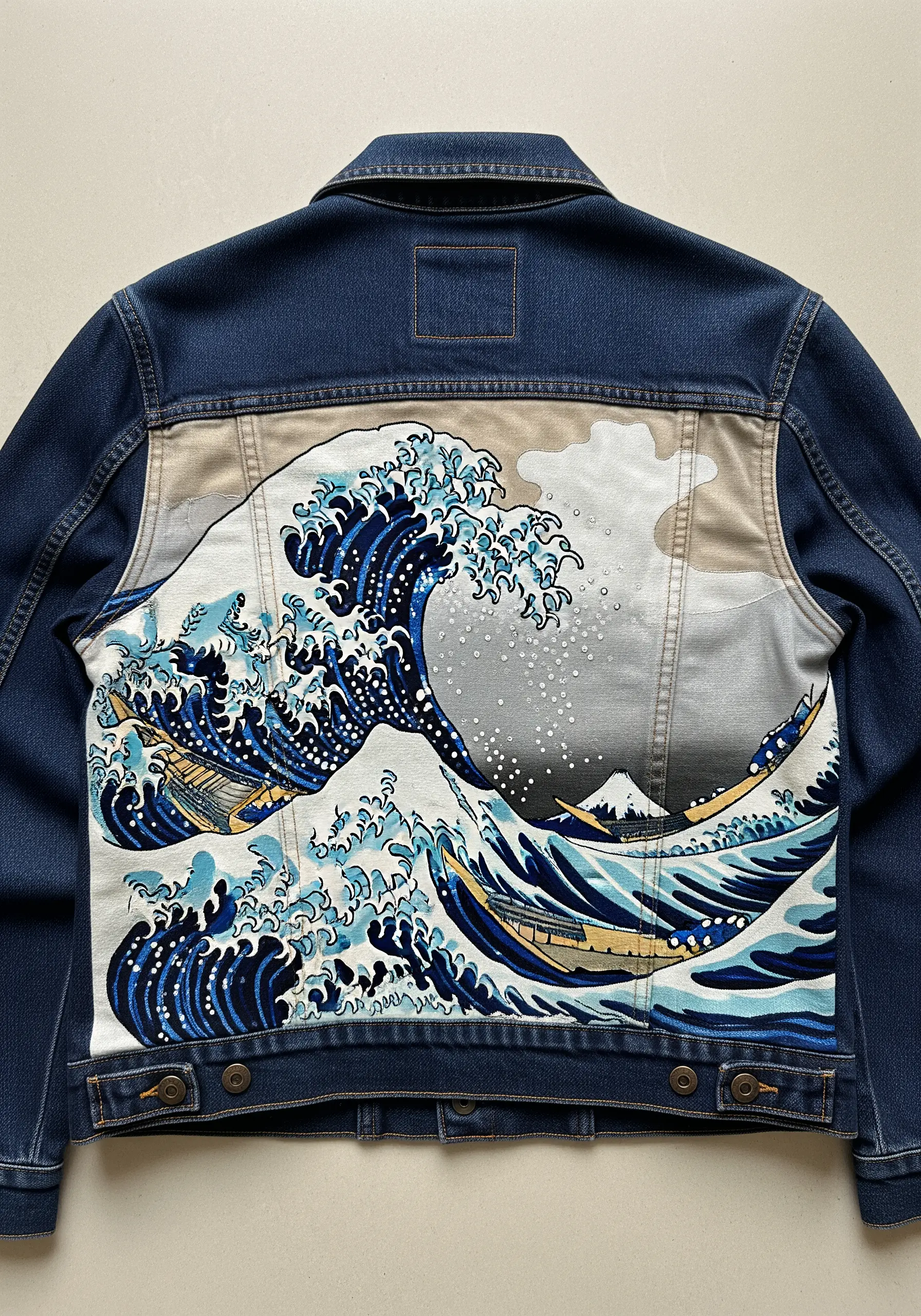 The Great Wave off Kanagawa design on a fabric panel stitched onto the back of a denim jacket.