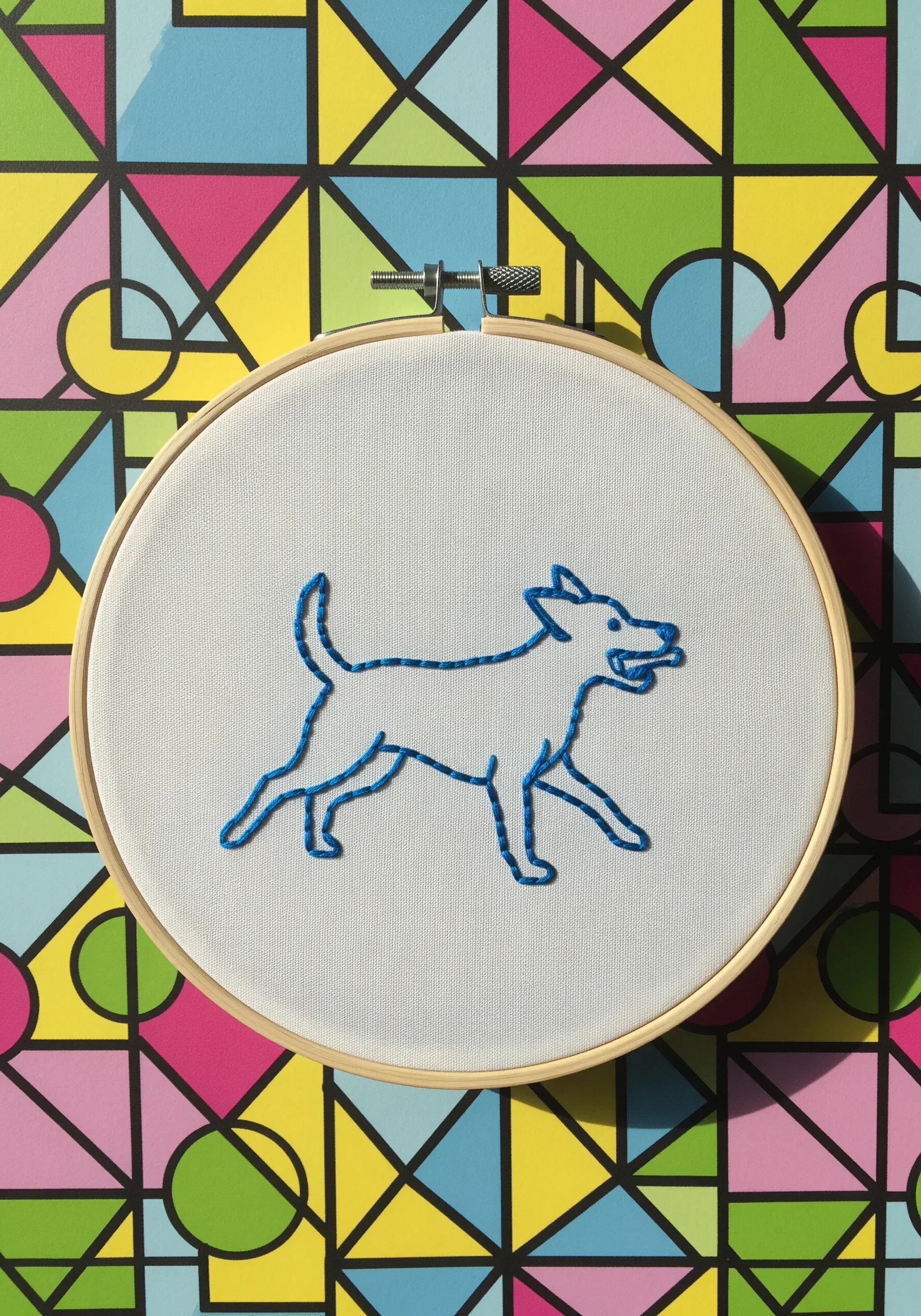 A bold, blue chain stitch outline of a trotting dog against a colorful background.