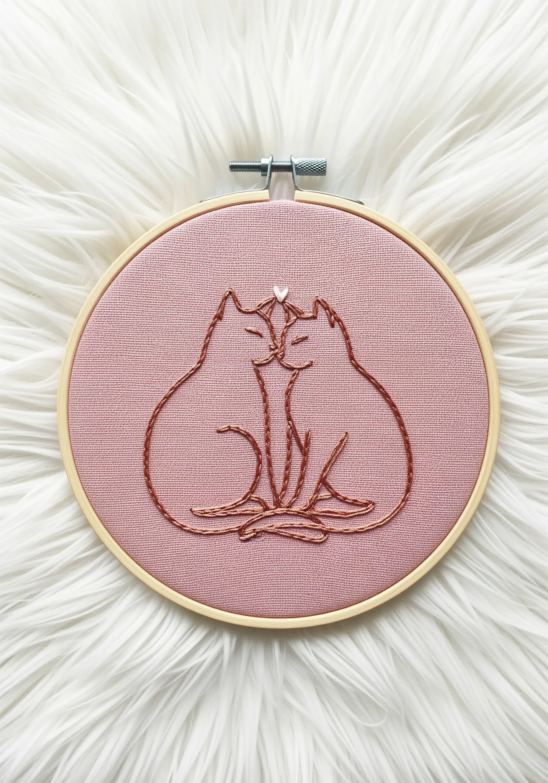 Line art embroidery of two cuddling cats with a tiny white heart detail.