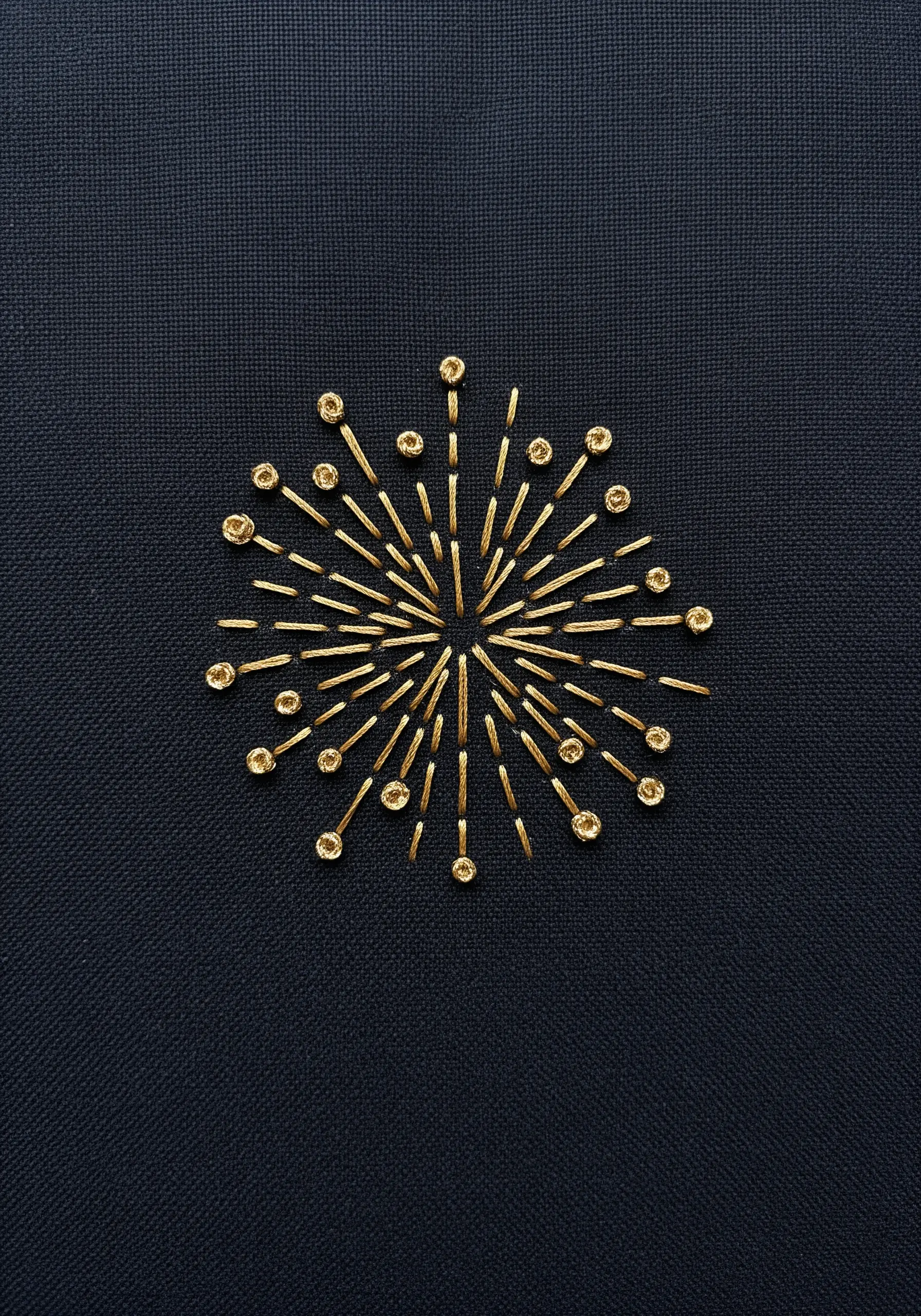 A firework burst made of radiating gold stitches, each tipped with a French knot.