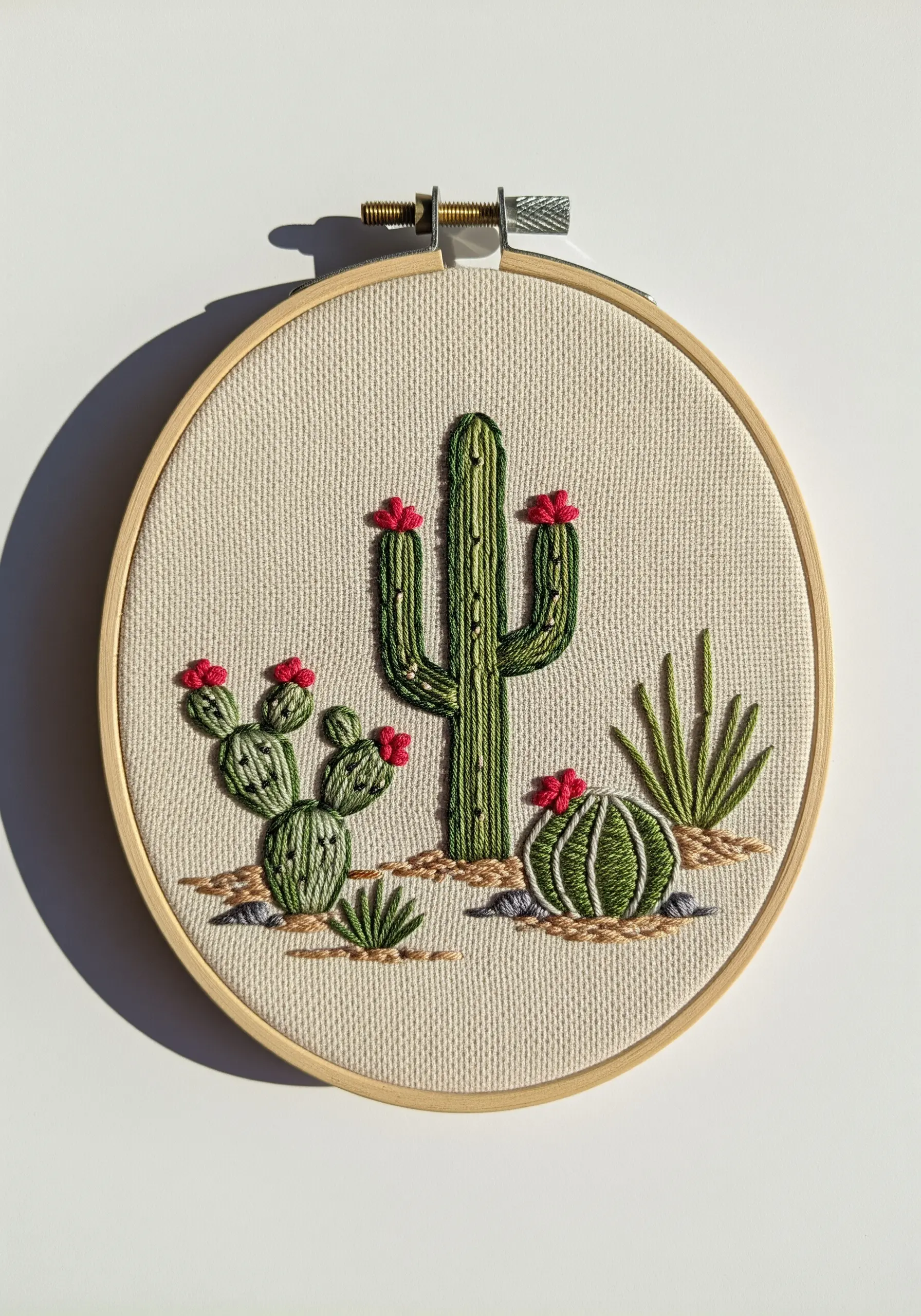 Embroidered desert scene with several types of cacti in various green tones.