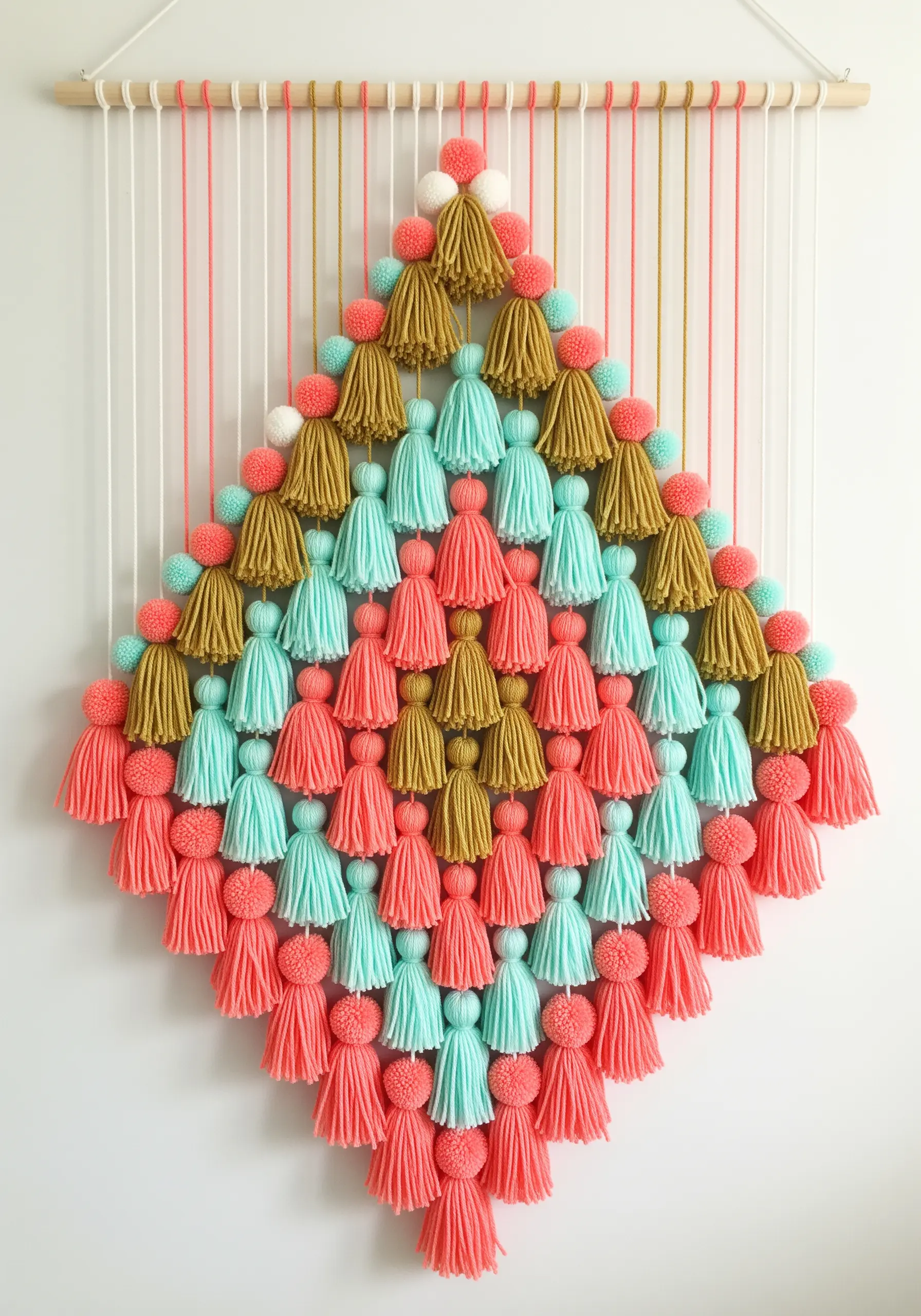 Wall hanging made of colorful tassels and pom-poms arranged in a large diamond shape.