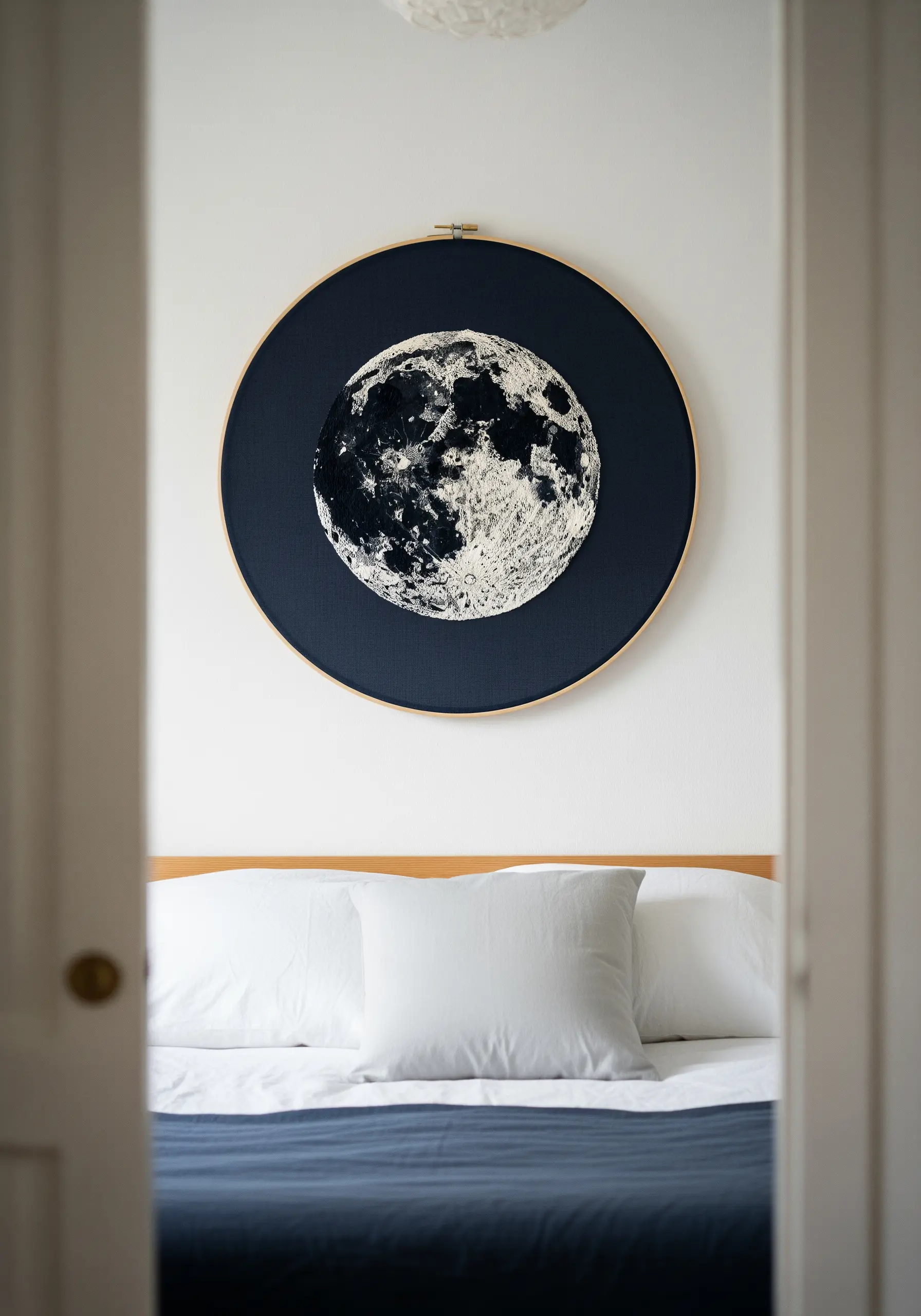 A highly textured embroidered moon with French knots, displayed in a large hoop.