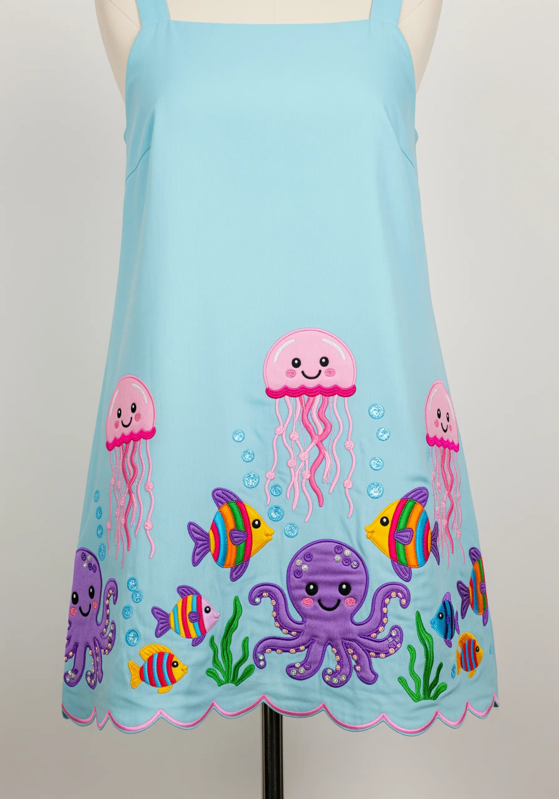 An underwater scene with a purple octopus, pink jellyfish, and rainbow fish embroidered on a blue dress