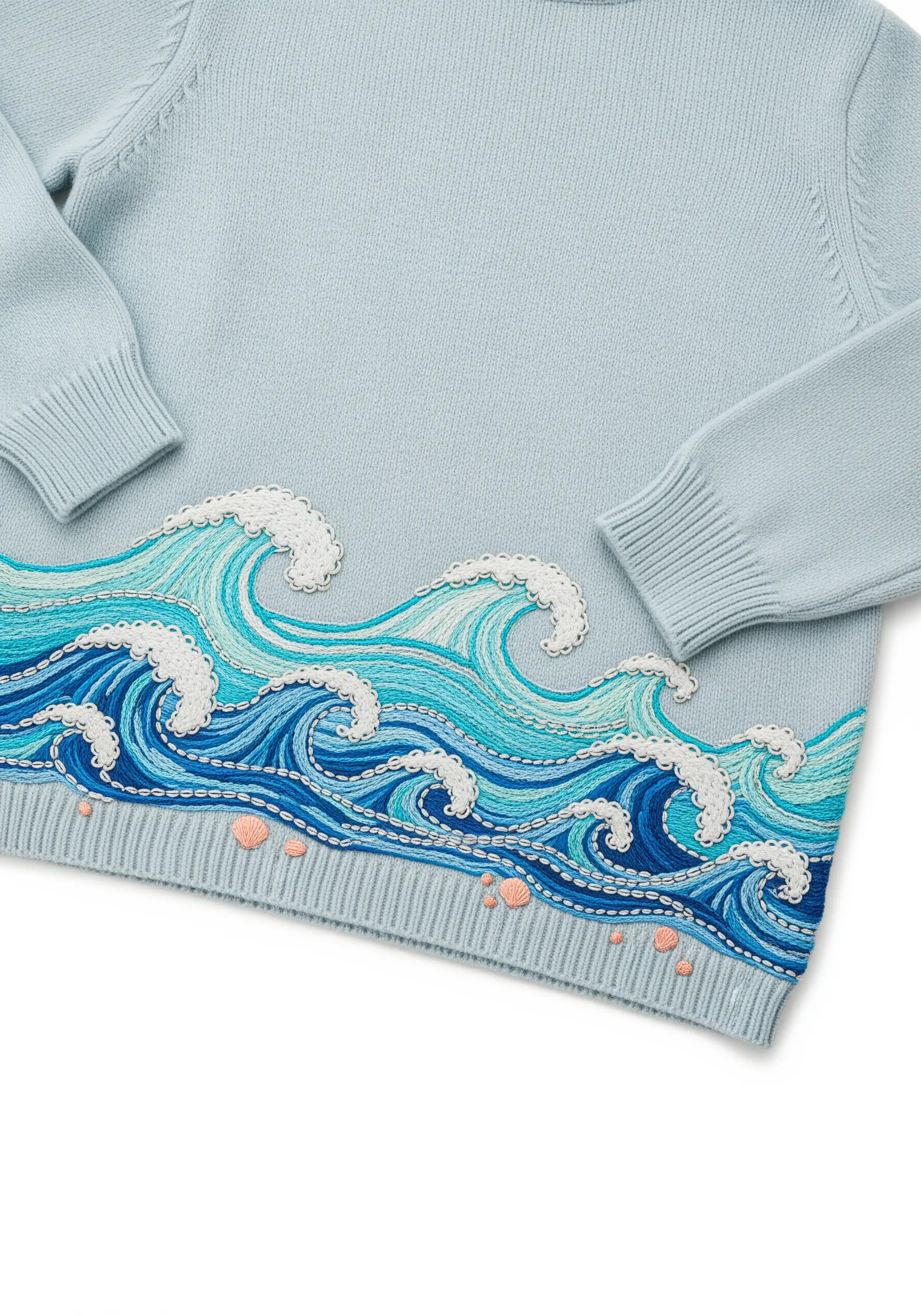 Stylized ocean waves embroidered in layers of blue along the hem of a light blue sweater.