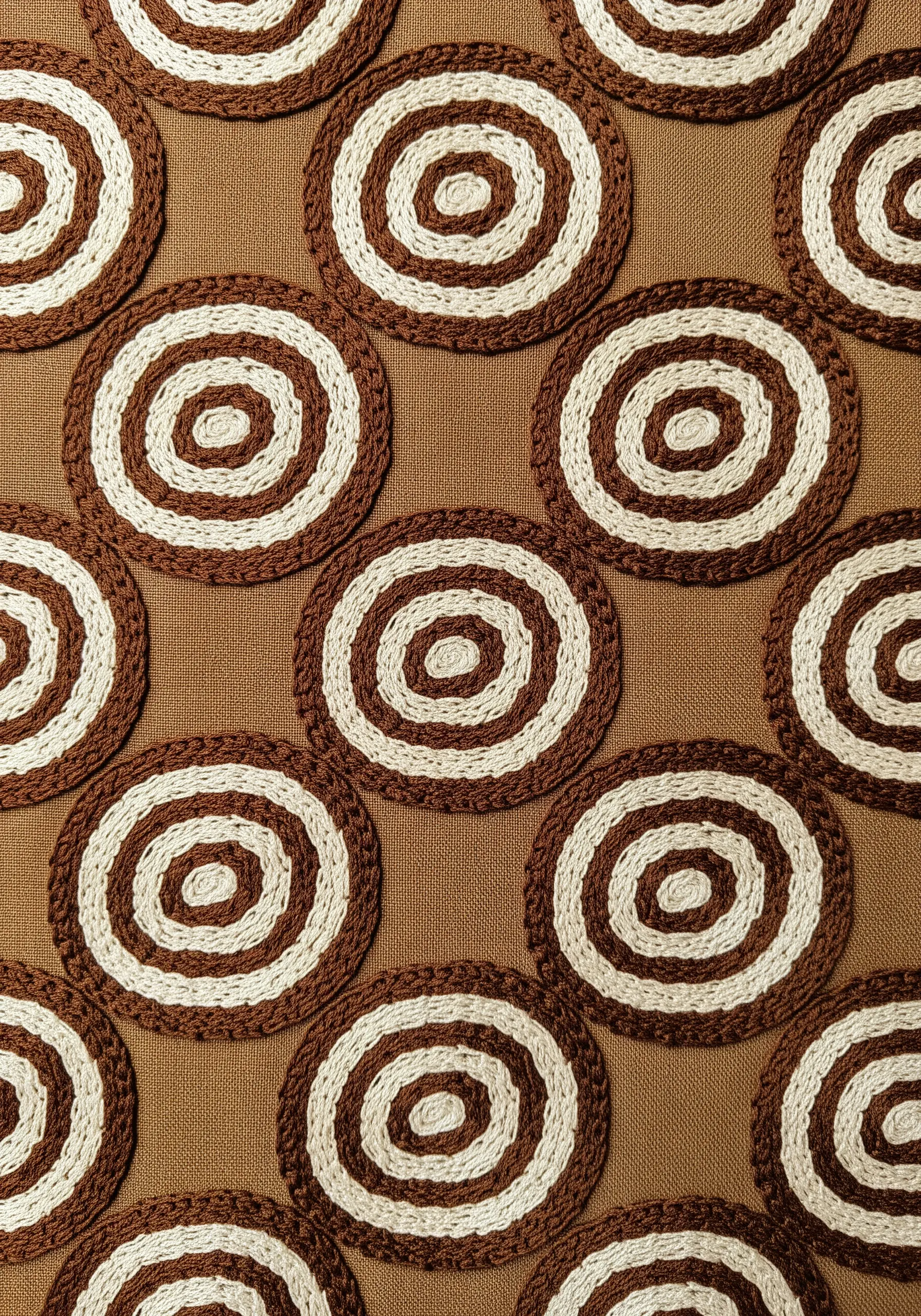 A repeating pattern of brown and white concentric circles made with a couching stitch.