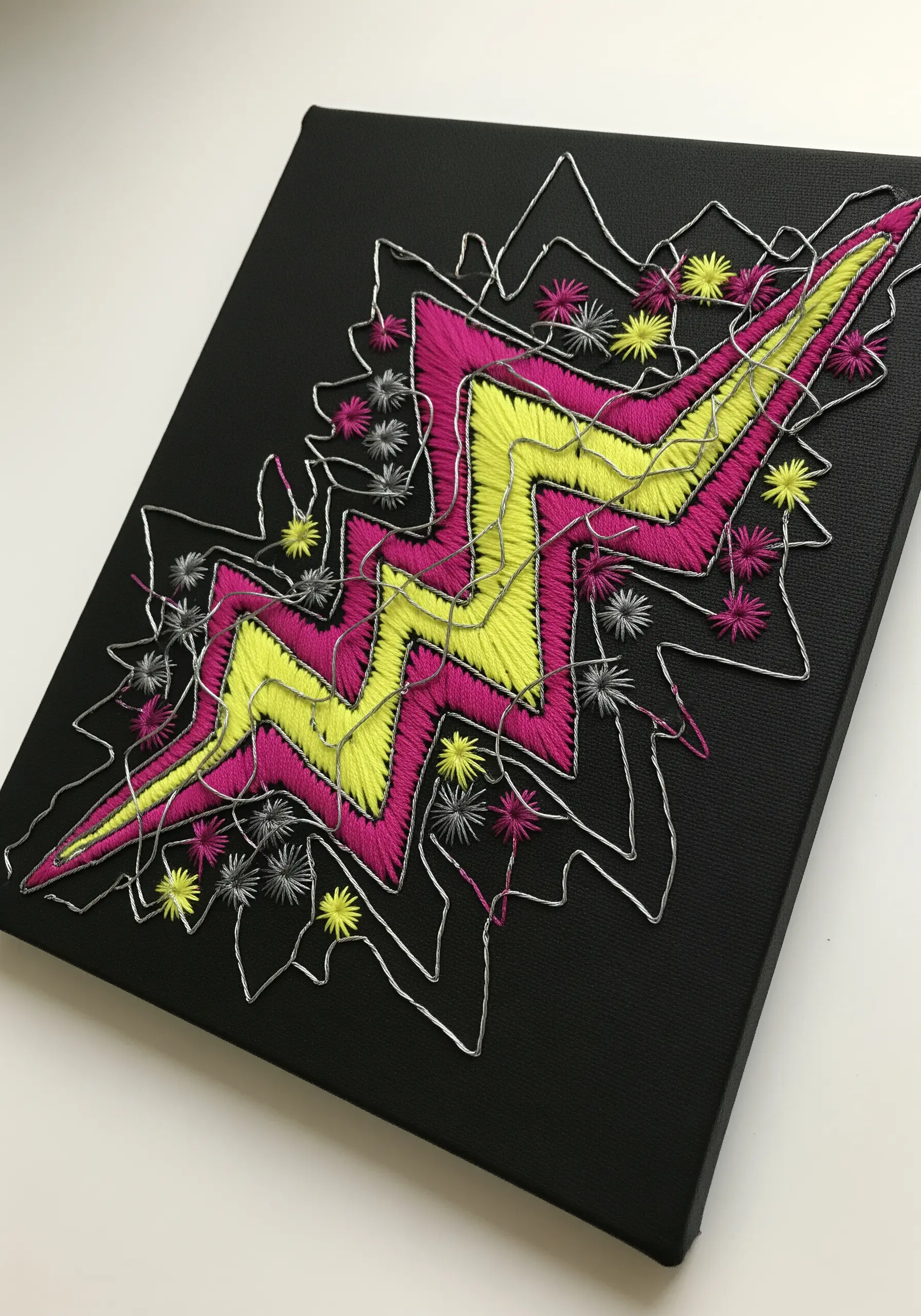 A vibrant lightning bolt embroidered on black canvas, outlined with bent silver wire for effect.