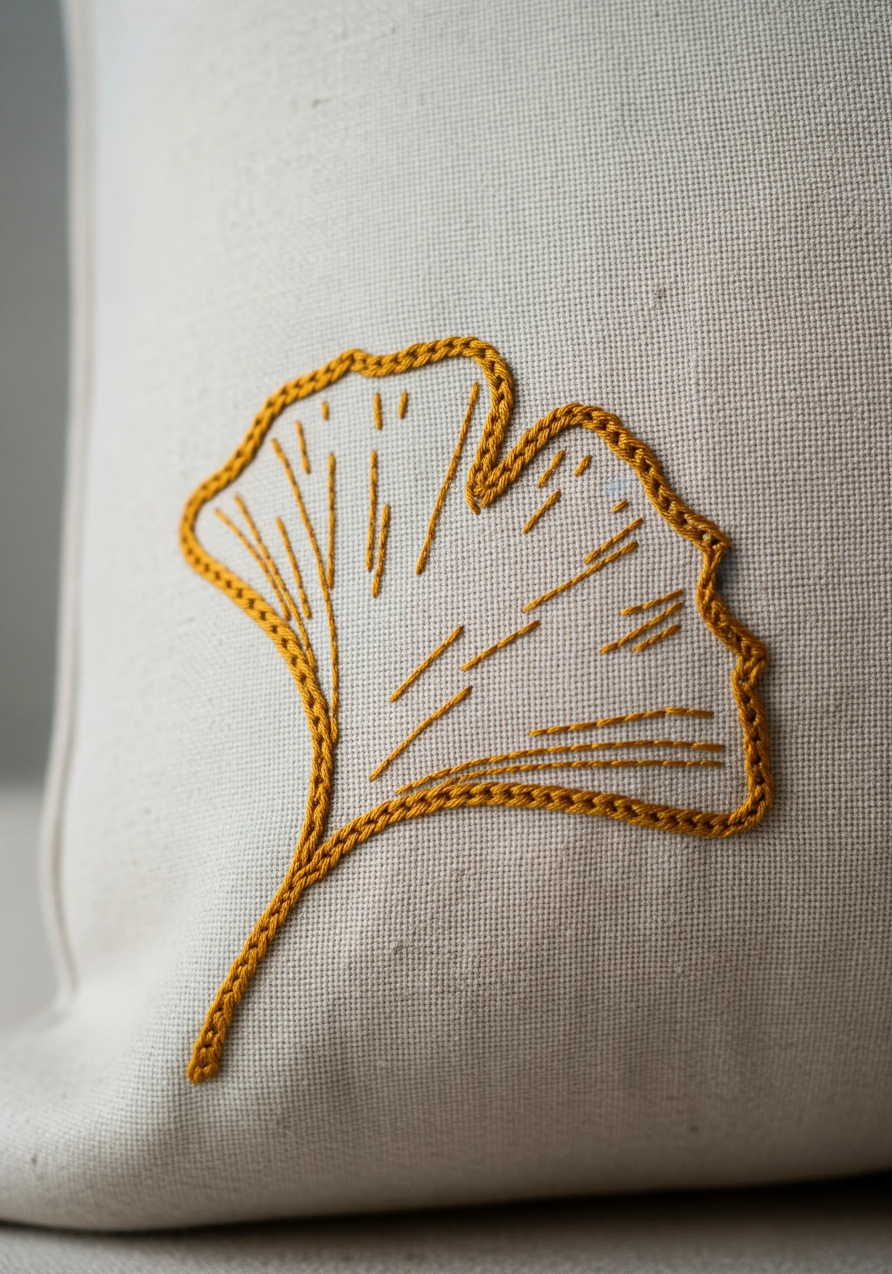 A ginkgo leaf embroidered in yellow with a stem stitch outline and straight stitch veins.