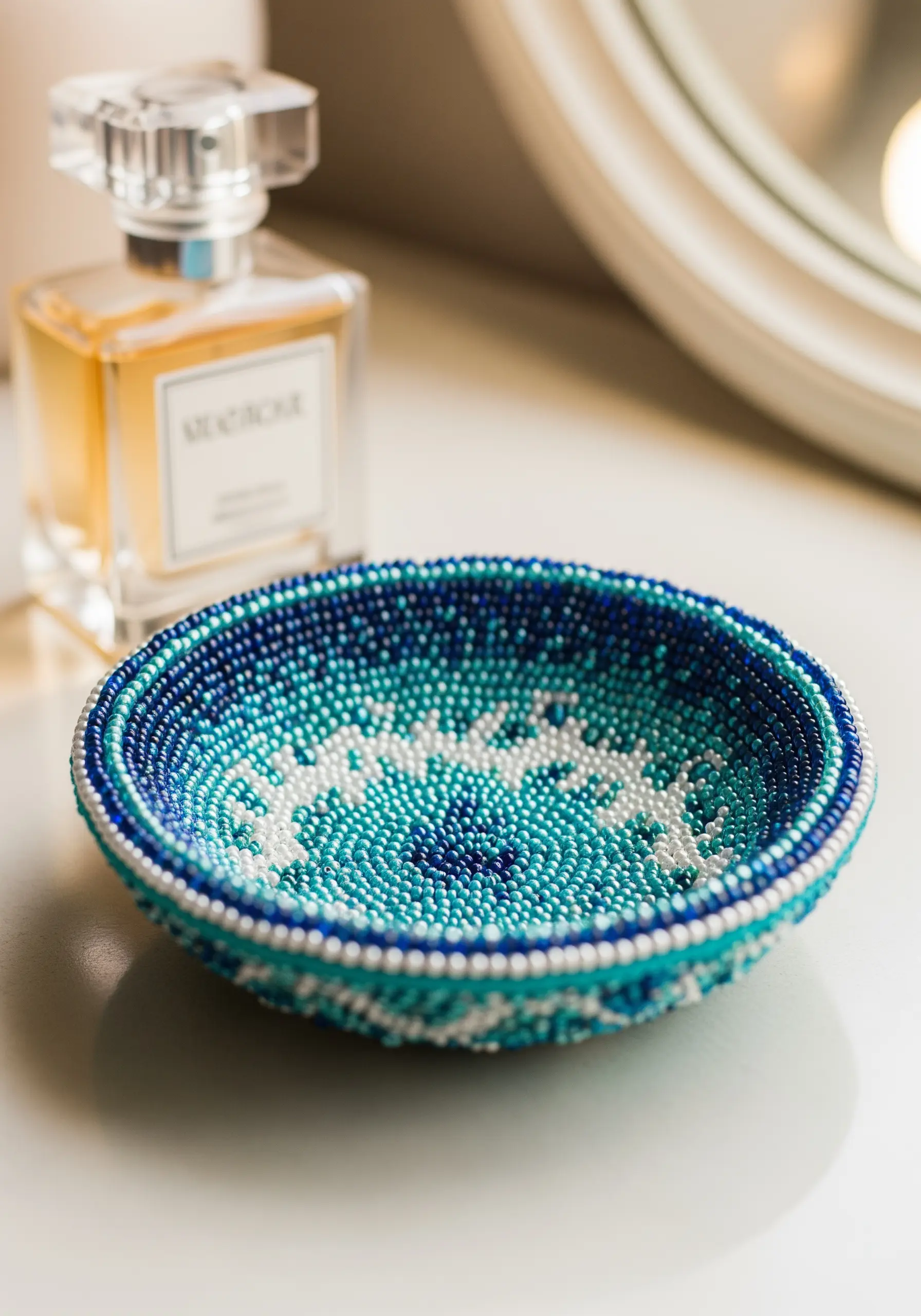 A small, round trinket dish completely covered in blue, teal, and white seed beads.