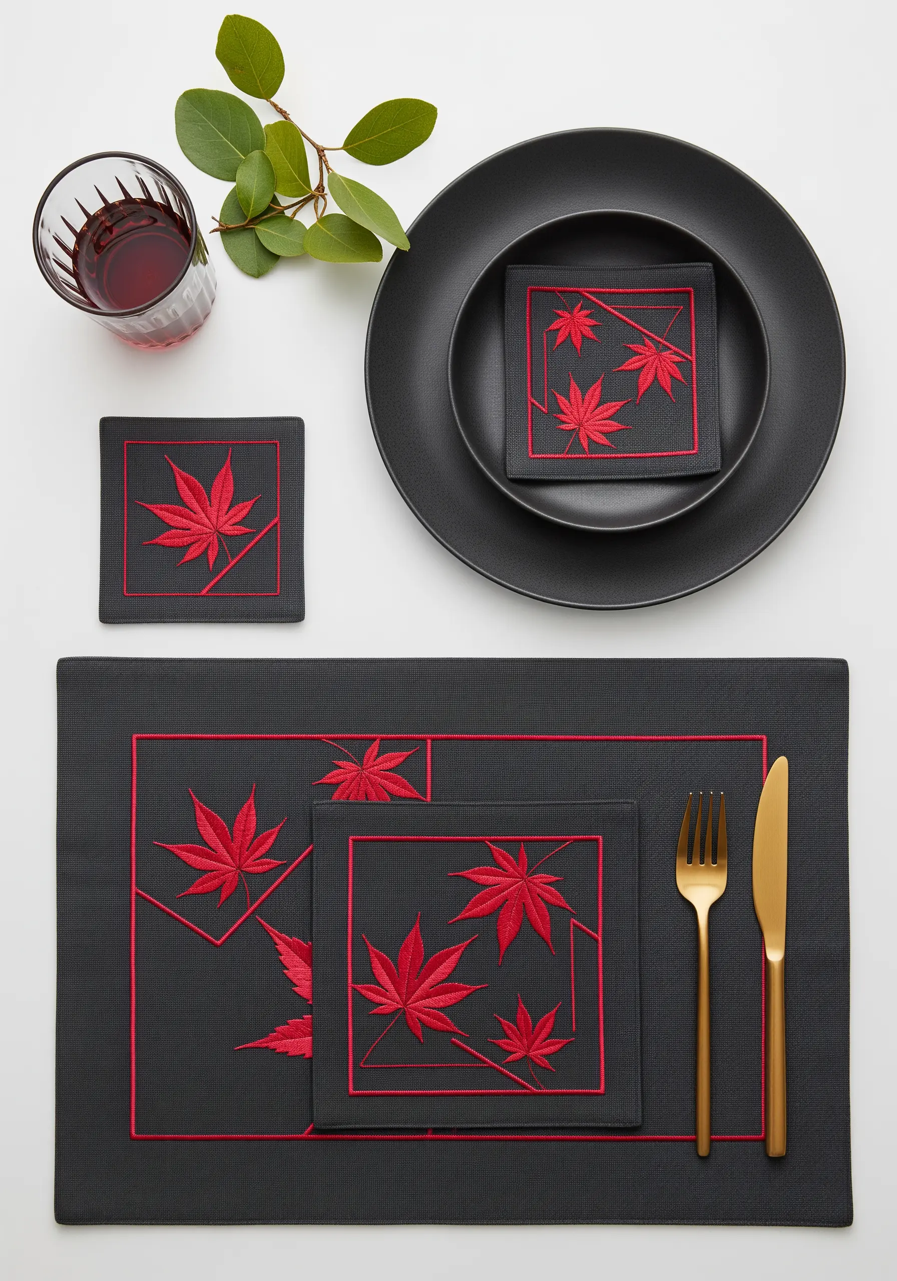A modern, dark table setting with placemats and napkins featuring bold red maple leaf embroidery