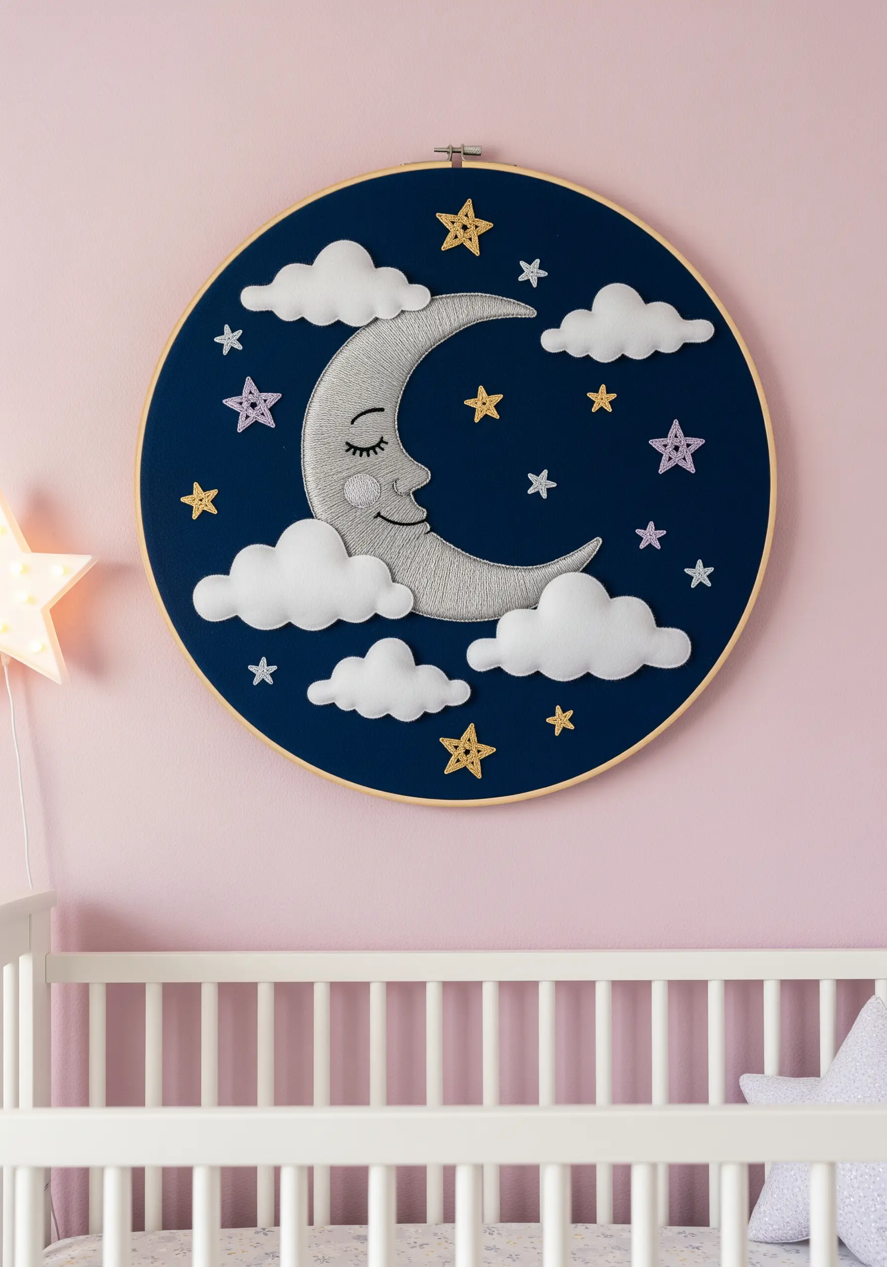 Nursery hoop art with a padded appliqué silver moon, soft white clouds, and embroidered stars.