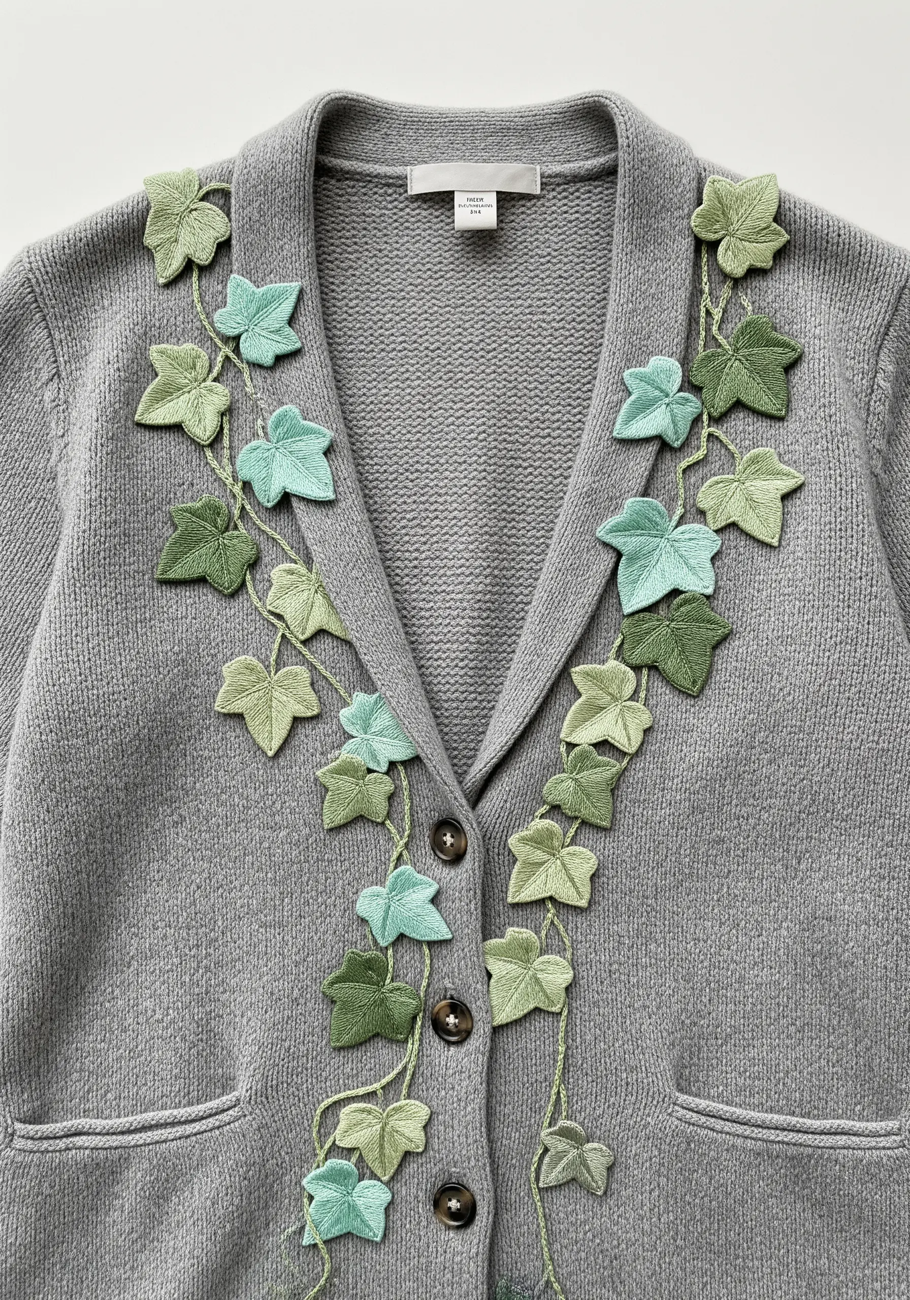 Appliqué ivy leaves in shades of green climbing the lapel of a grey cardigan.