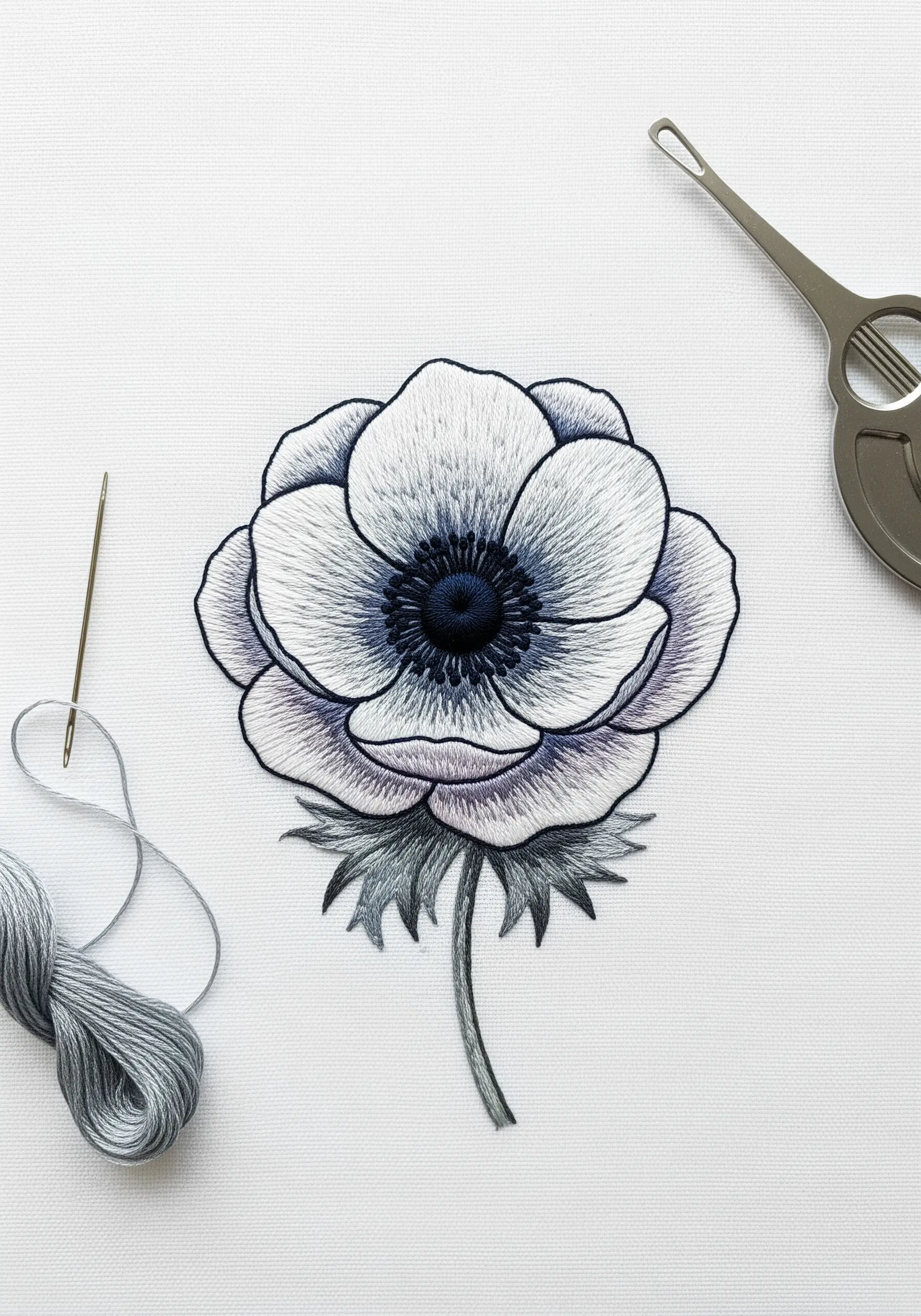 A white and grey anemone with a dark center, stitched to look like a watercolor painting.