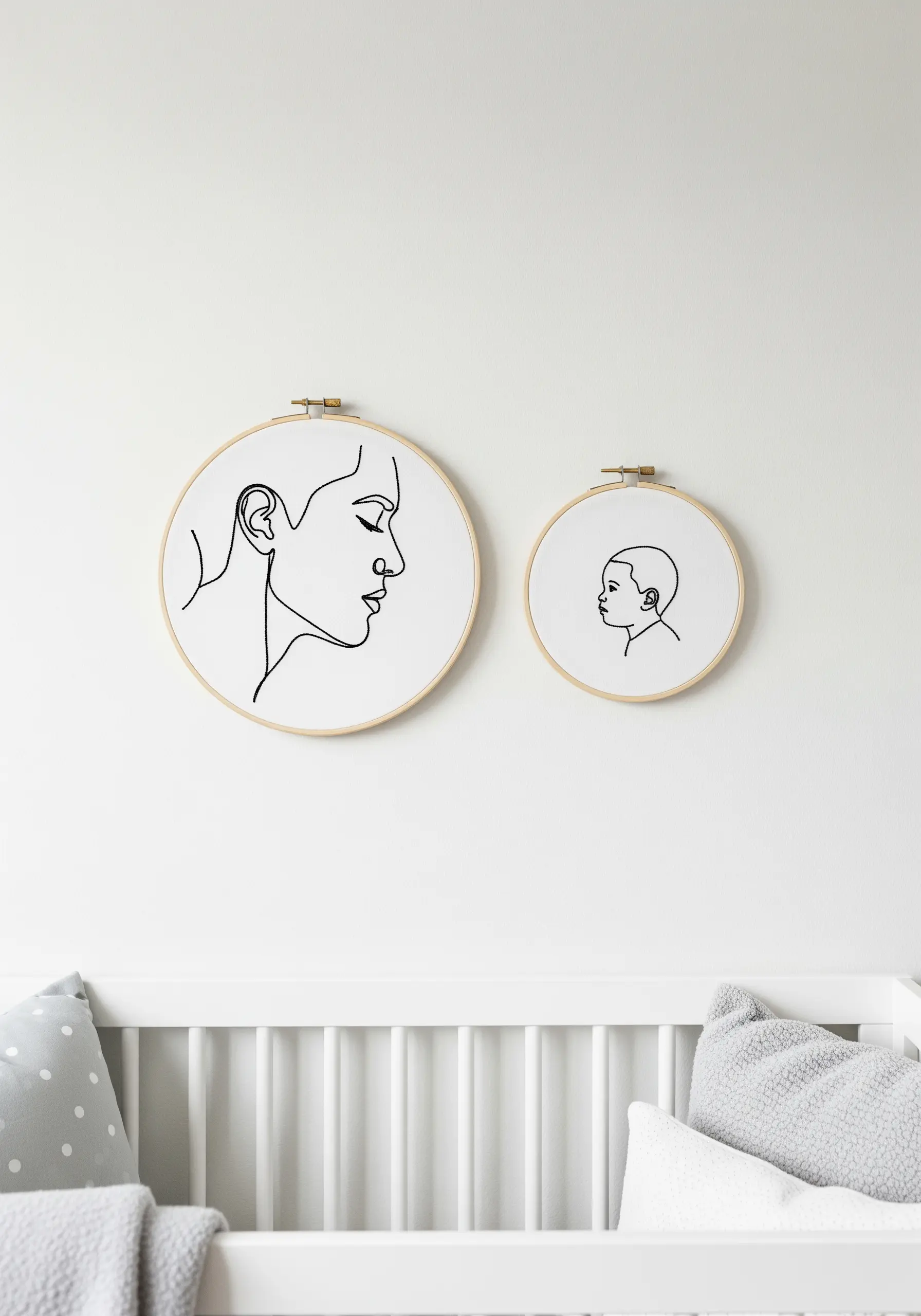 Two separate embroidery hoops, one with a mother's profile and one with a child's, hung together.