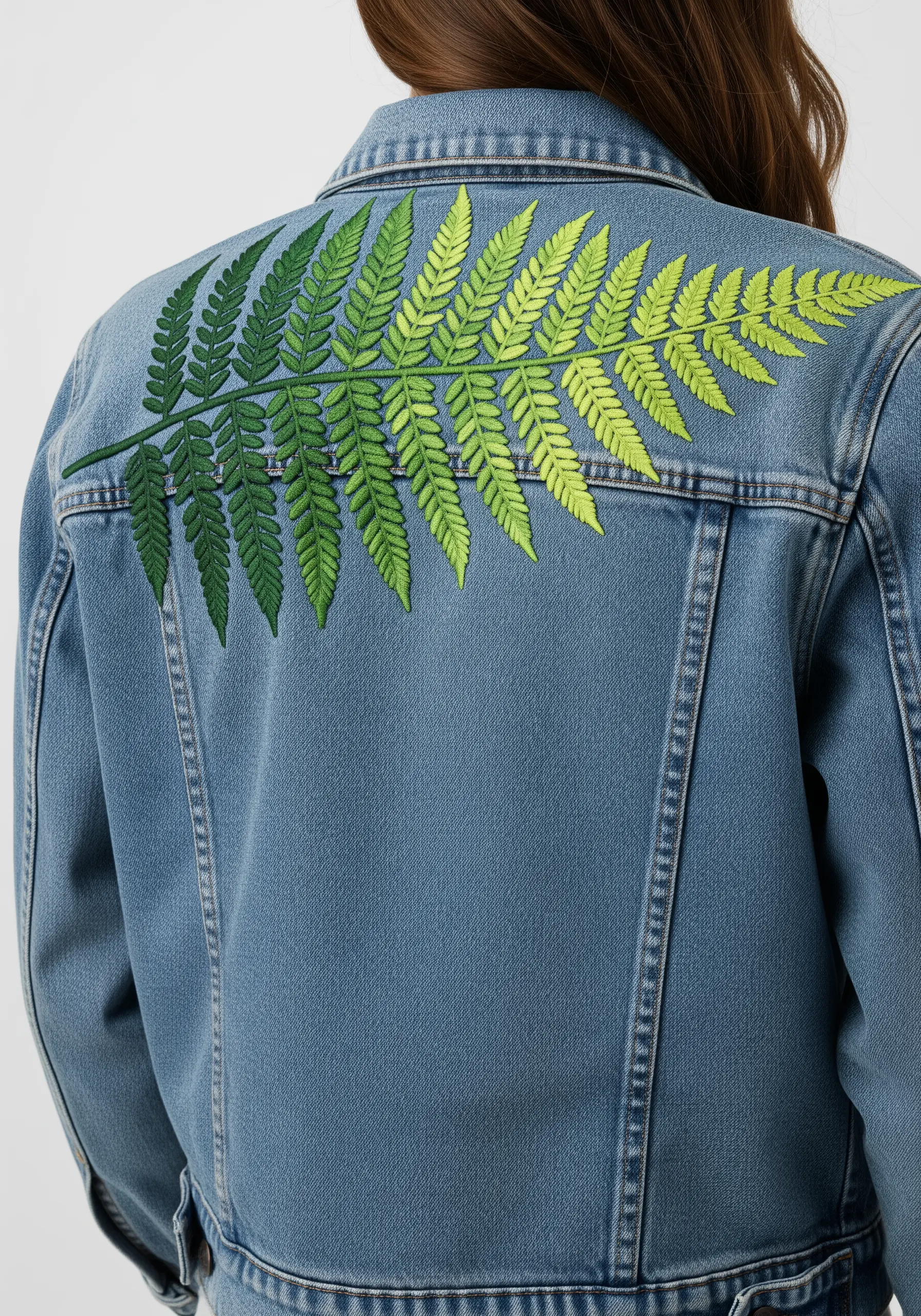 Large fern embroidered on the back of a denim jacket with a gradient from dark to lime green.