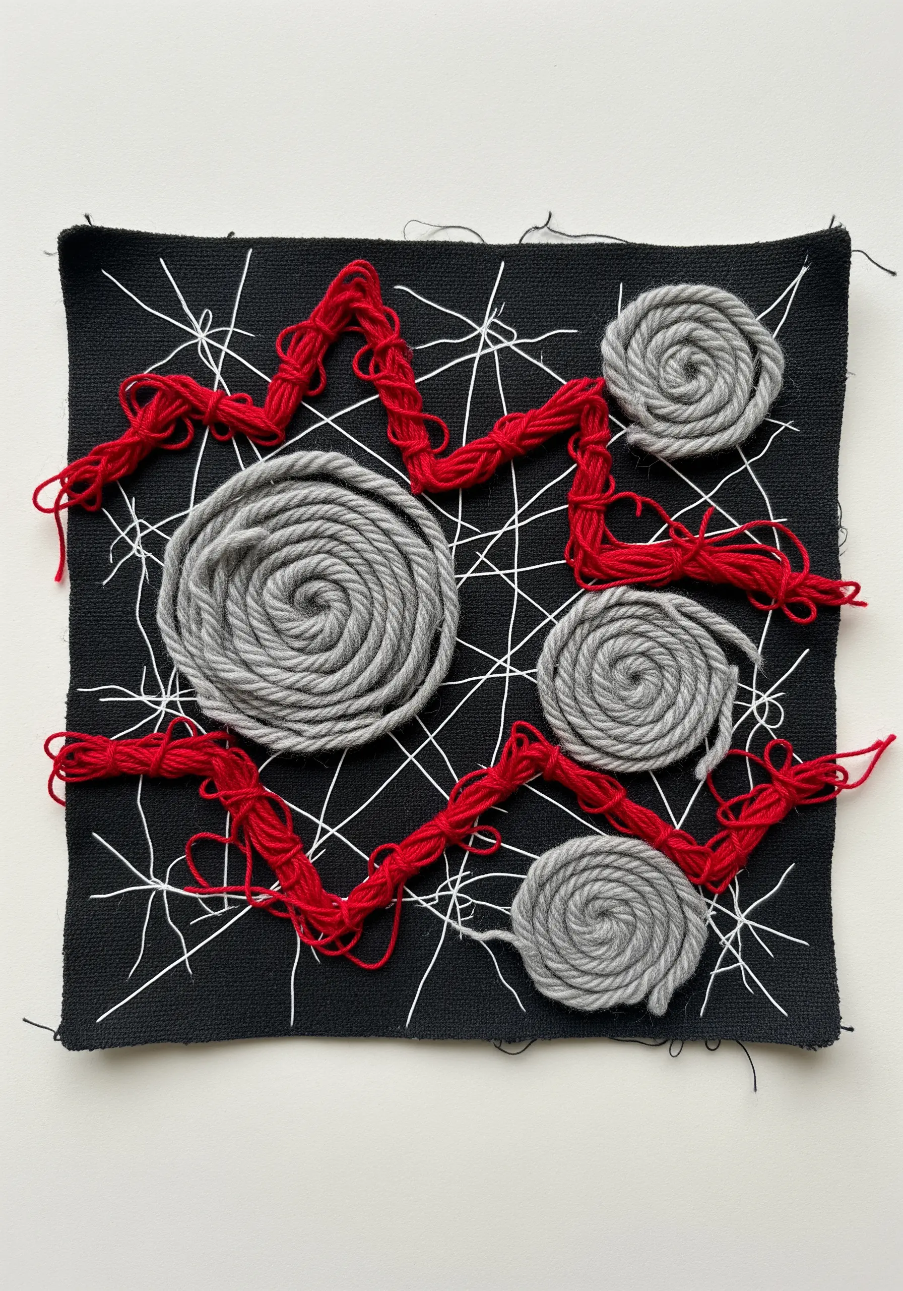 High-contrast embroidery with thick grey yarn spirals and red zigzags over a web of fine white lines.