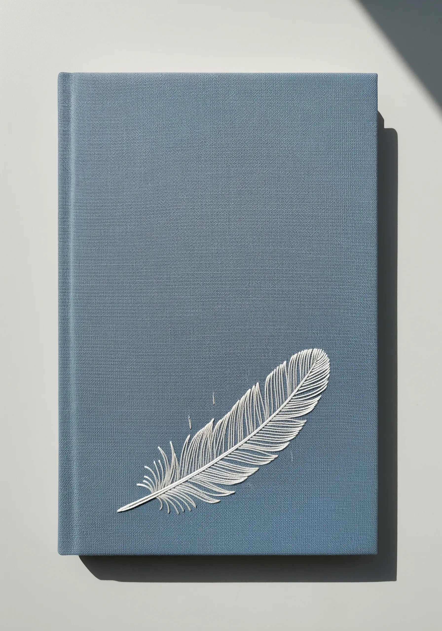 A delicate white feather embroidered with fine split stitches on a blue book cover.