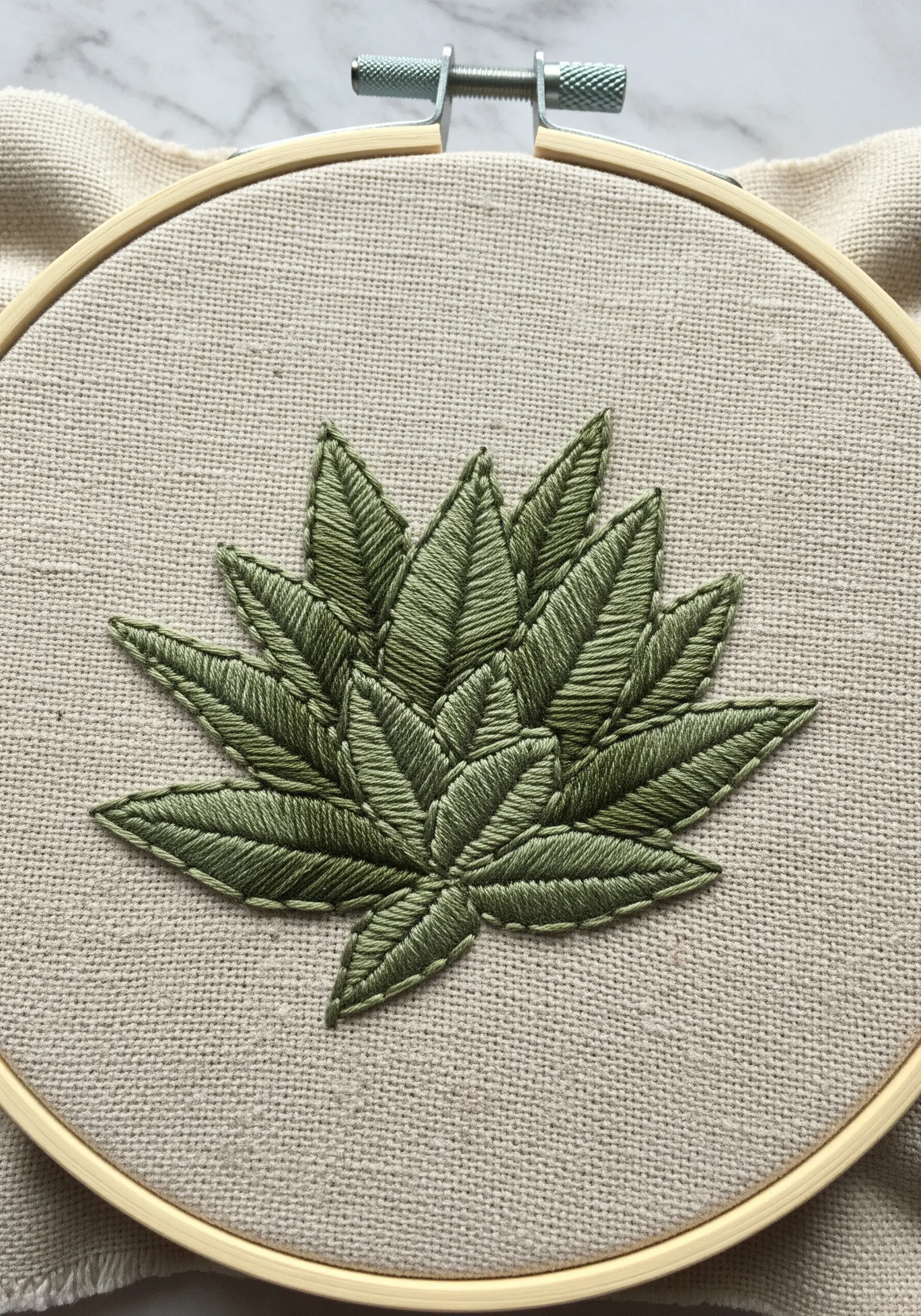 A layered leaf motif embroidered in shades of green using the fishbone stitch.