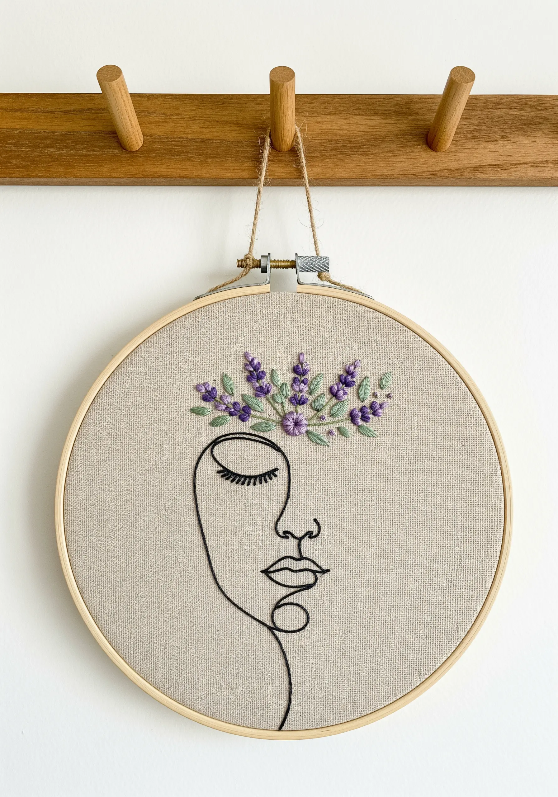 A minimal line art face with a crown of delicately embroidered lavender flowers and green leaves.