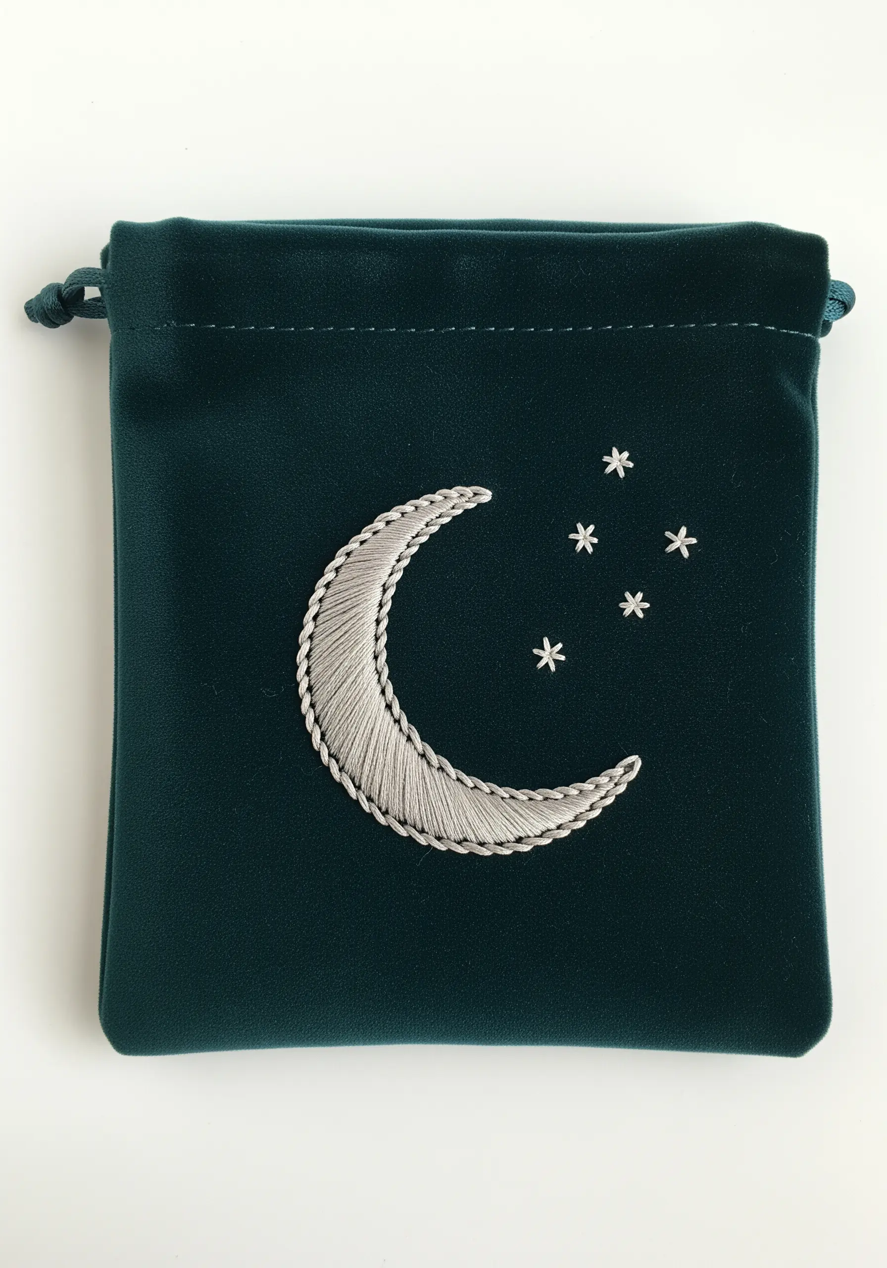 Satin-stitched crescent moon with a silver outline on a dark green velvet pouch.