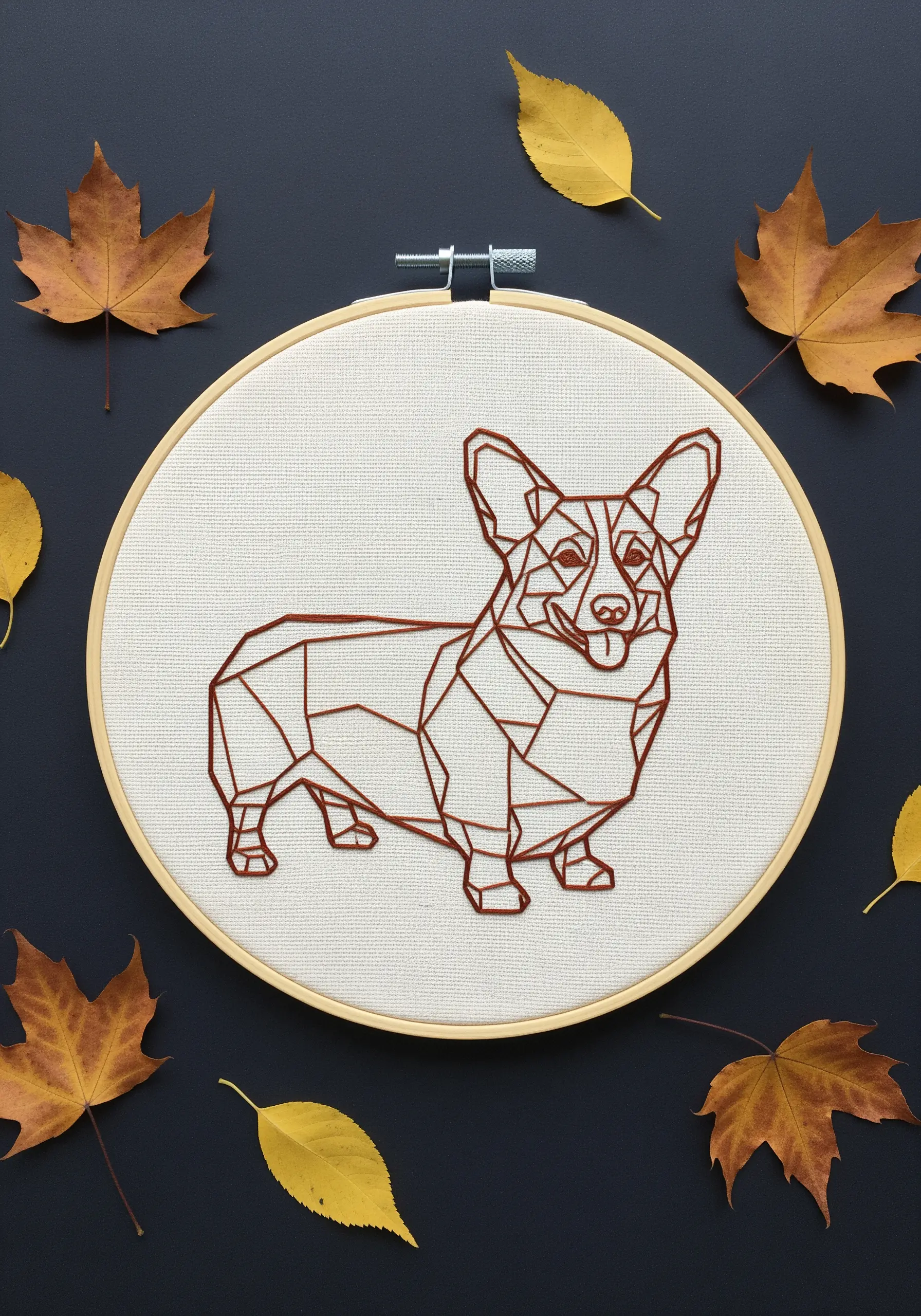 Geometric line art embroidery of a Corgi, surrounded by autumn leaves.
