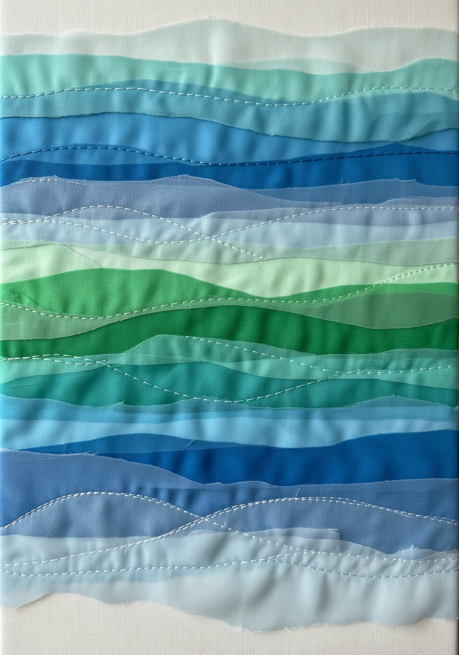 An abstract textile piece with layered strips of wavy blue and green sheer fabric.