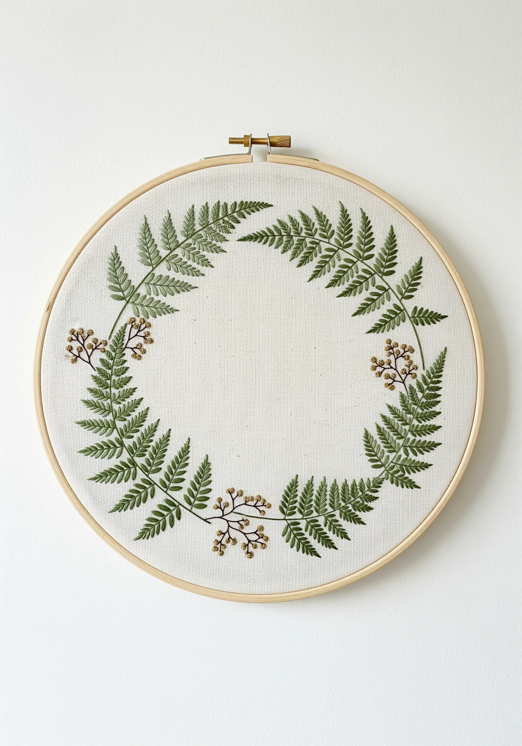 A circular wreath of embroidered fern fronds with small clusters of brown knots.