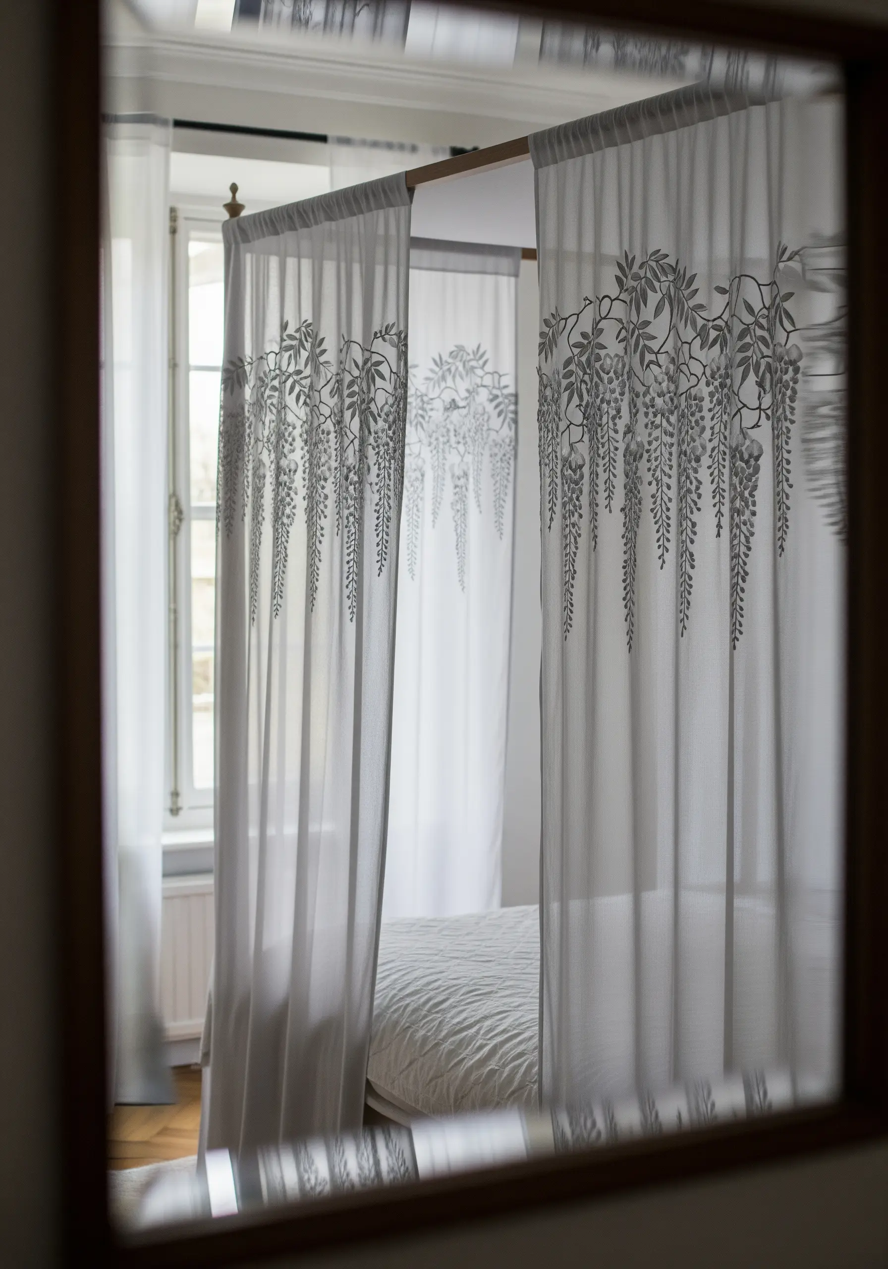 Cascading wisteria vines embroidered in grey on sheer white bed canopy curtains.