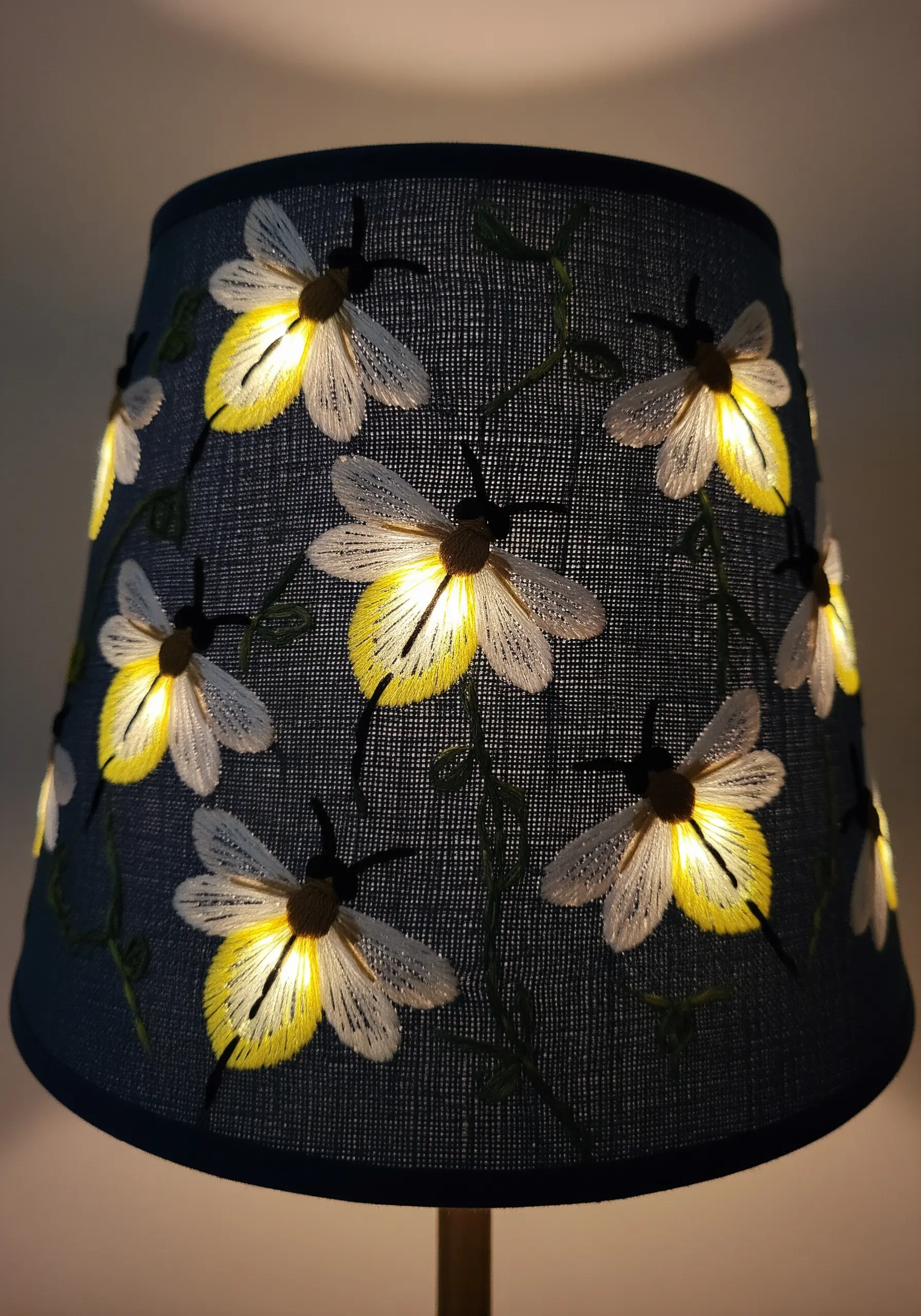 An embroidered lampshade with fireflies that glow when the light is on.