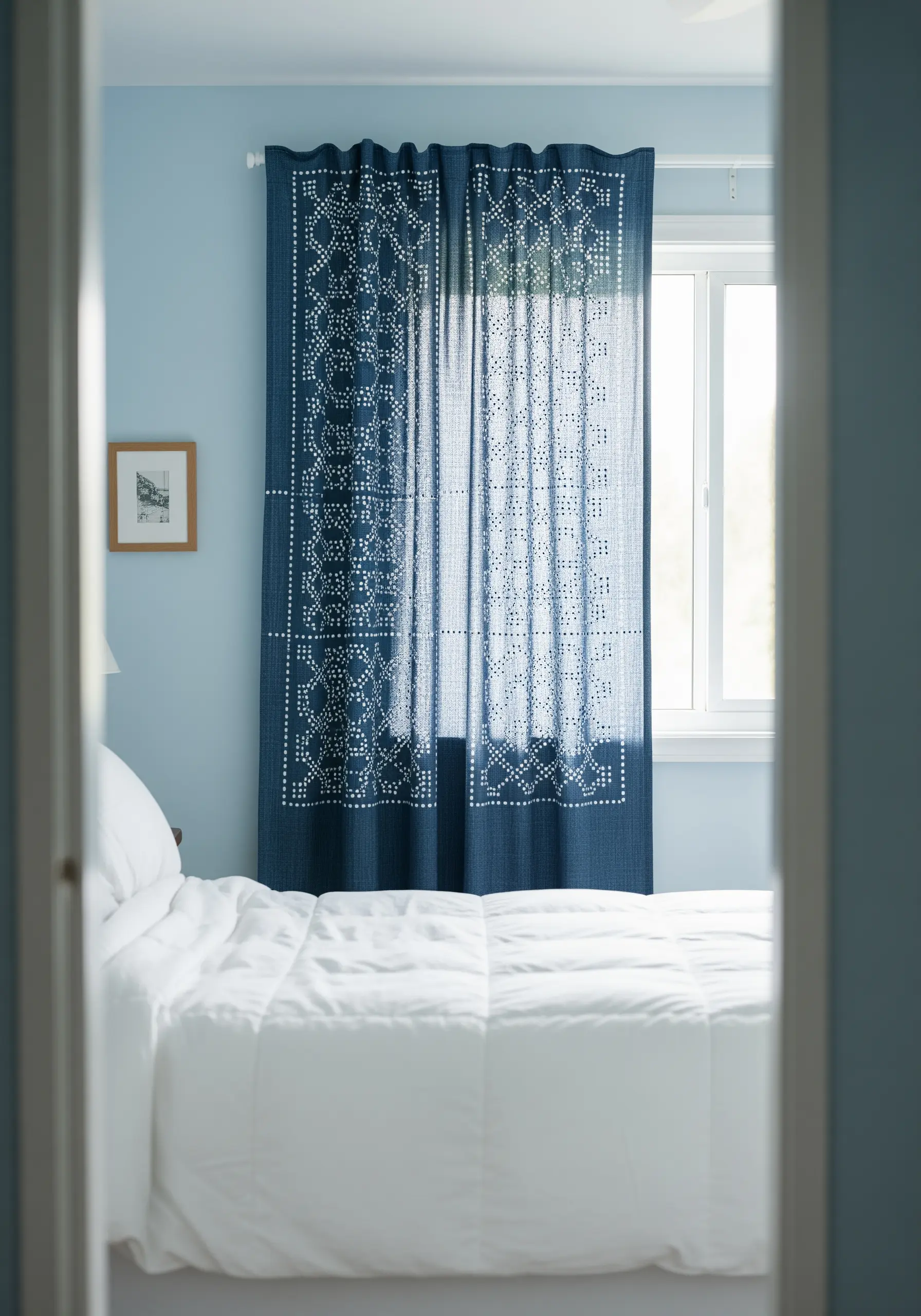 White geometric patterns embroidered on dark blue curtains, backlit by a window.
