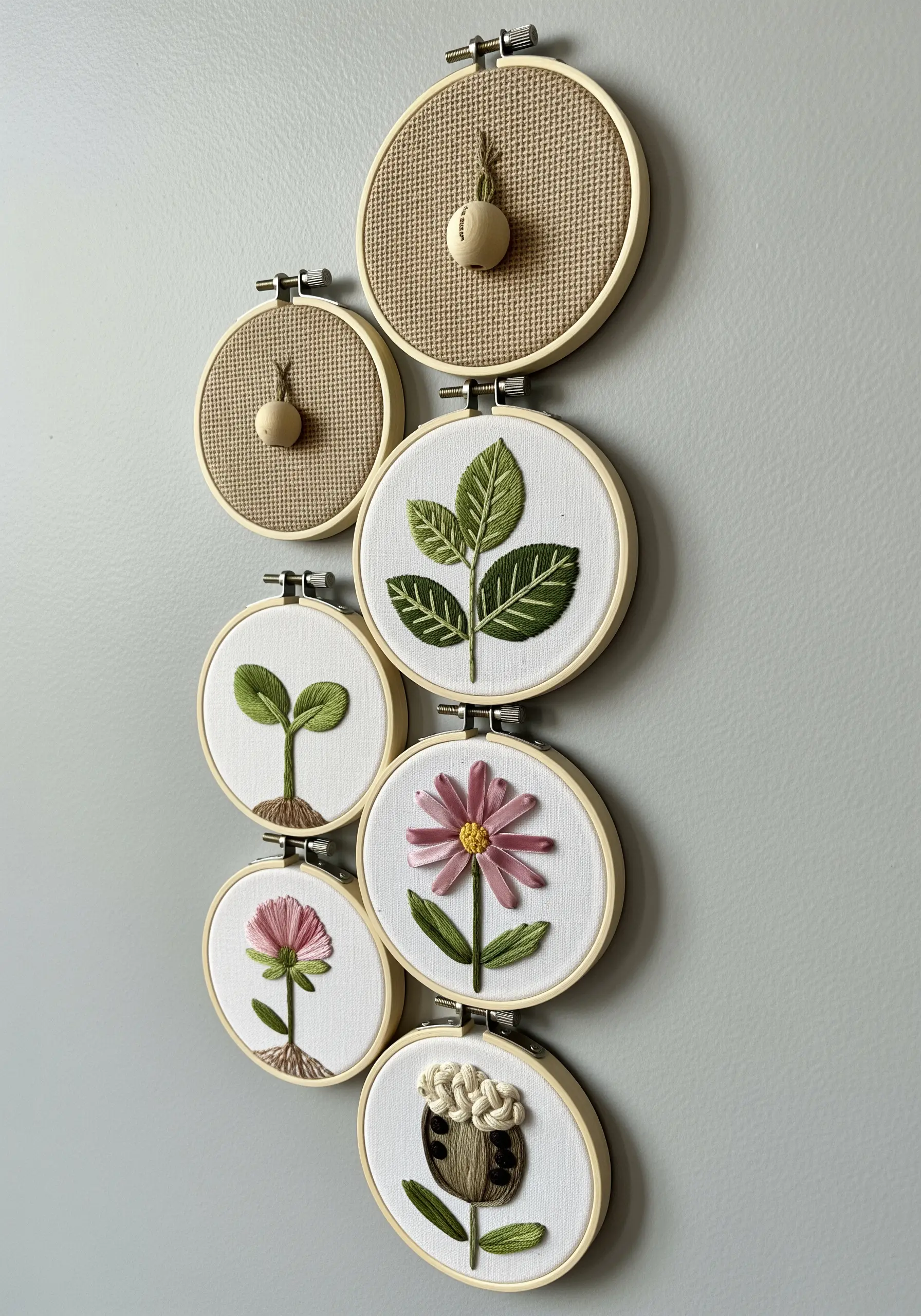 A series of small embroidery hoops showing the life cycle of a plant, from seed to flower.