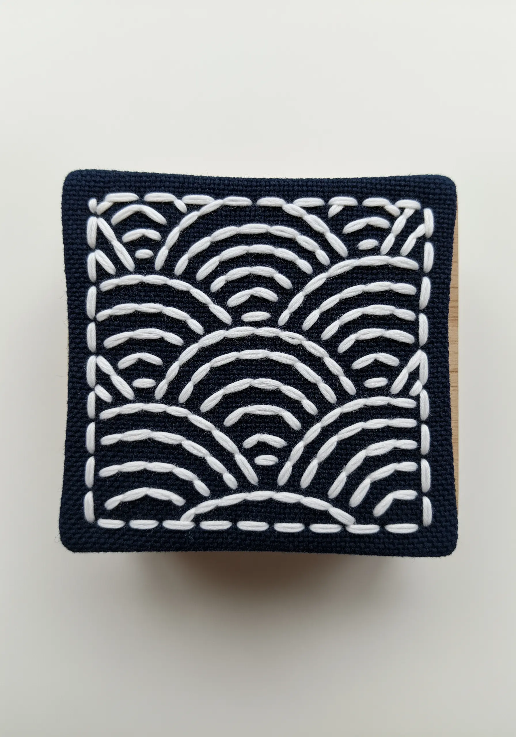 Japanese Sashiko embroidery with a white wave pattern on dark navy fabric.
