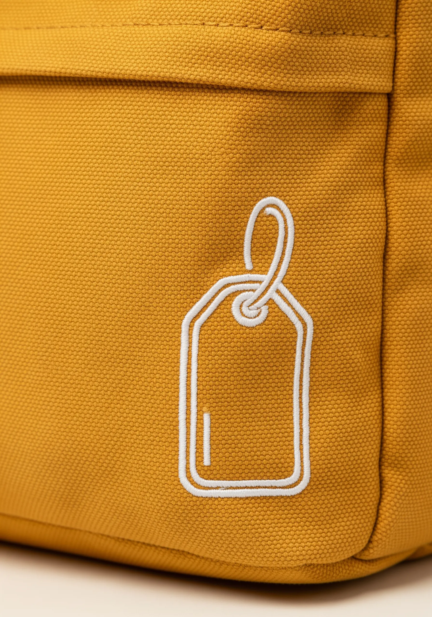 A white luggage tag outline with a raised, dimensional effect on a yellow canvas backpack.