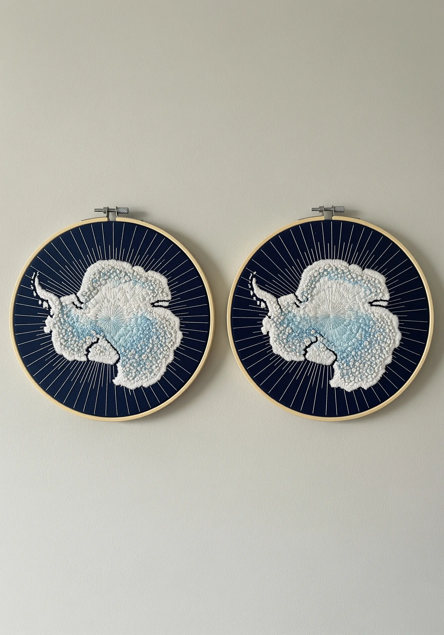 Two hoops showing embroidered maps of Antarctica with textured French knots and radiating stitches.