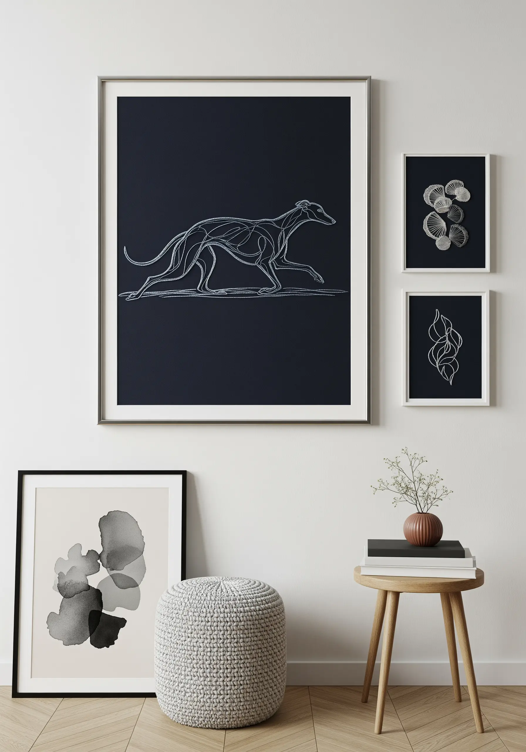 Fine-line embroidery of a running greyhound on dark fabric, framed on a gallery wall.