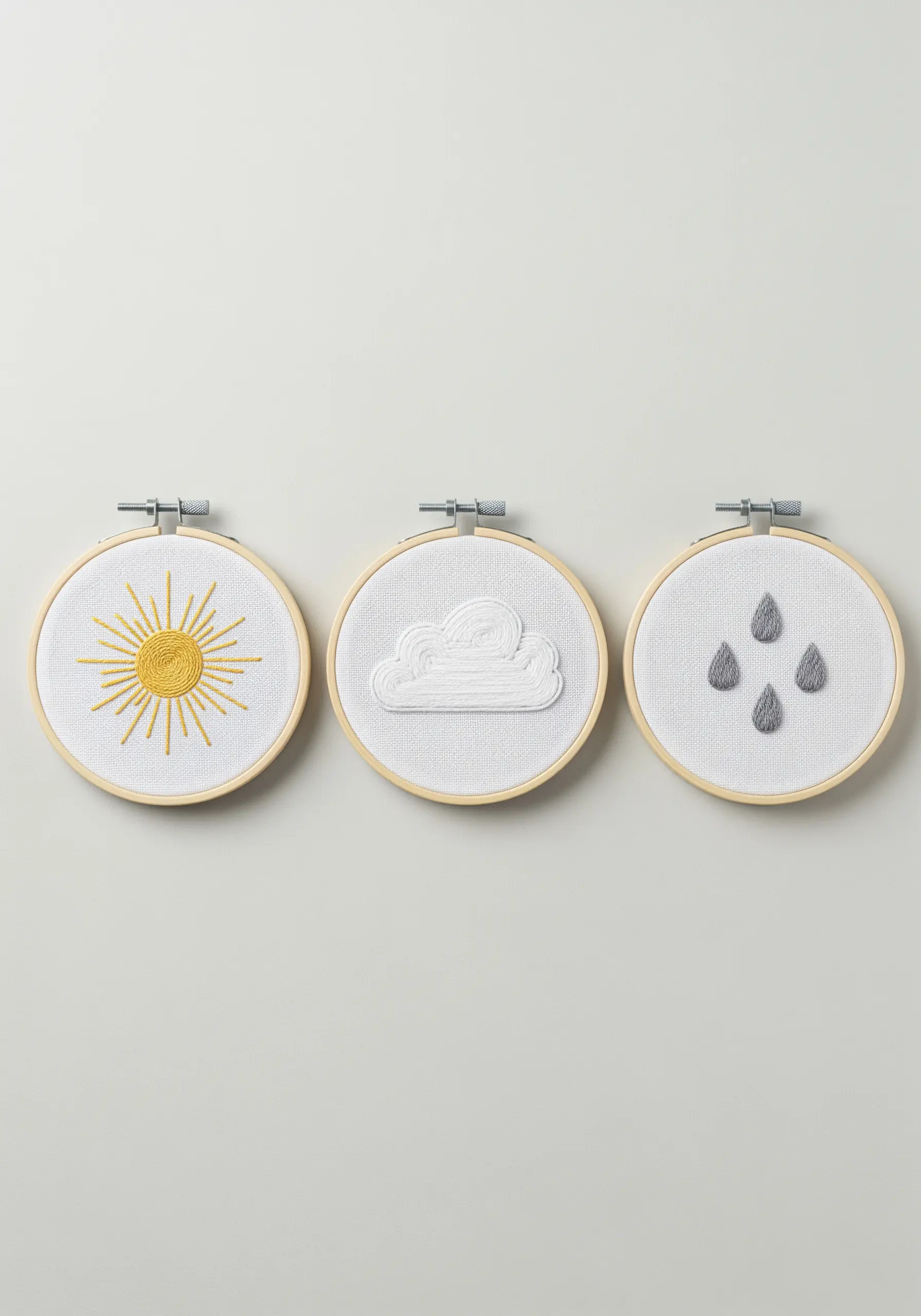 Three embroidery hoops with raised white-on-white weather icons: sun, cloud, and raindrops.