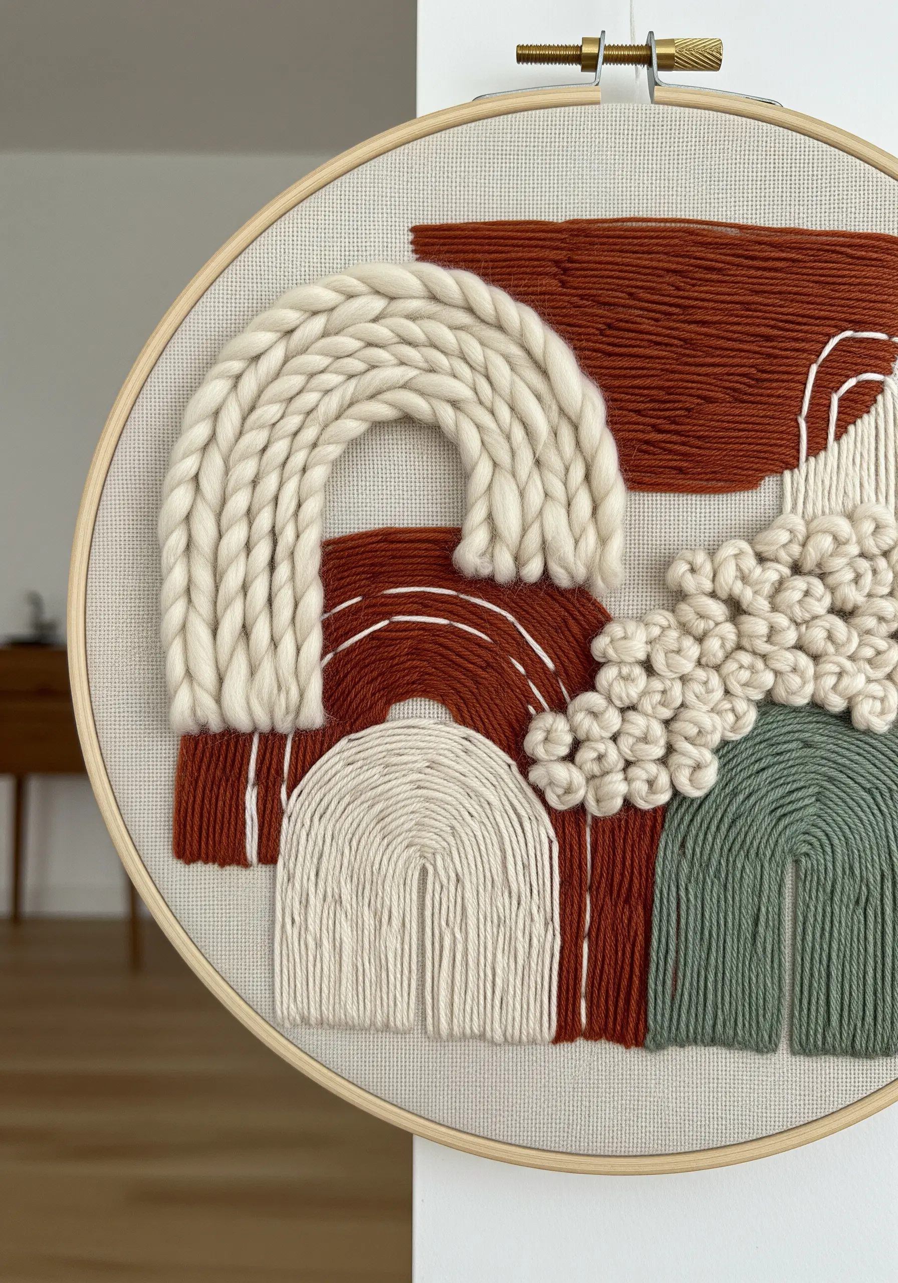 Abstract hoop art combining thick yarn rainbows, French knots, and fabric blocks.