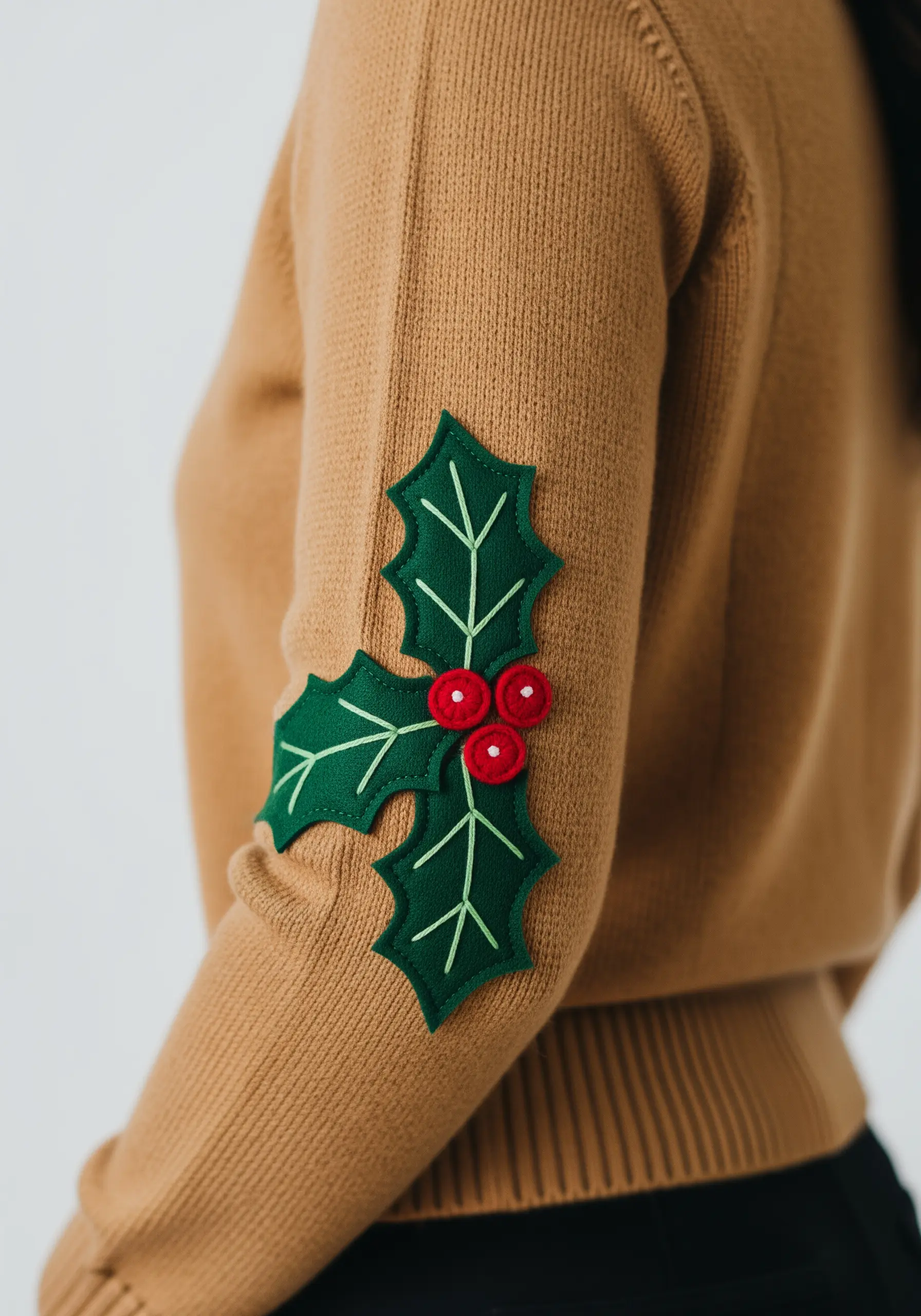 Green felt holly leaves with red berries appliquéd as an elbow patch.